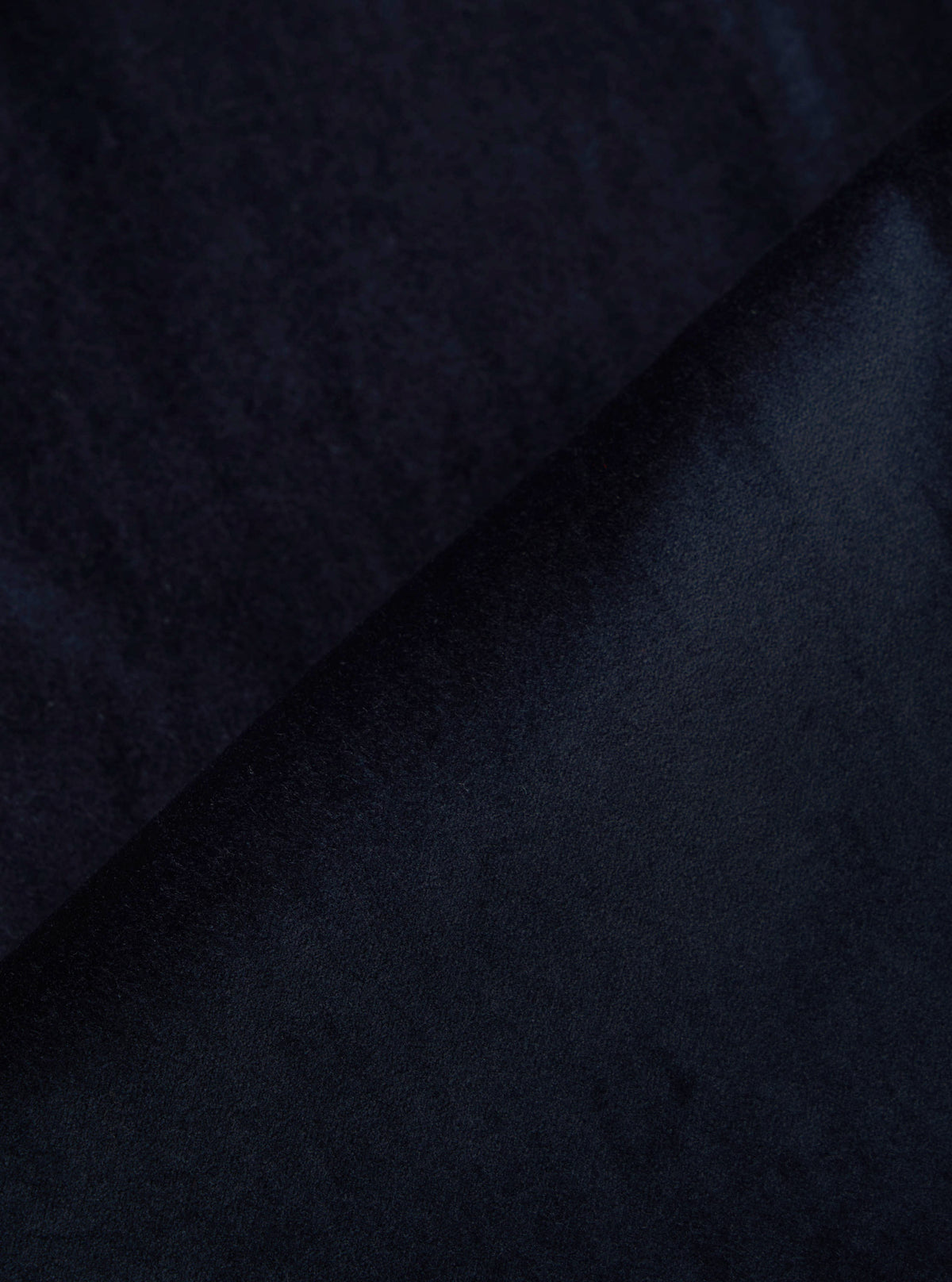 Close-up of the Navy Velveteen Oxford Pant fabric. The rich, dark navy velveteen material is folded, showcasing its soft texture and luxurious sheen.