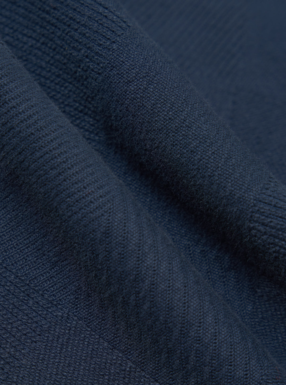 Close-up of the Dark Navy Patchwork Weave Cotton Pleated Track Pant fabric, showing the texture and color. The material is draped to highlight its weave.