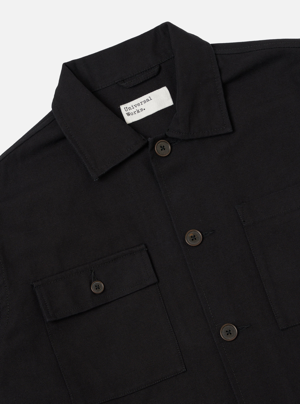 Close-up of the Black Organic Canvas Dockside Overshirt on a white background. The shirt has a button-down front and two chest pockets.