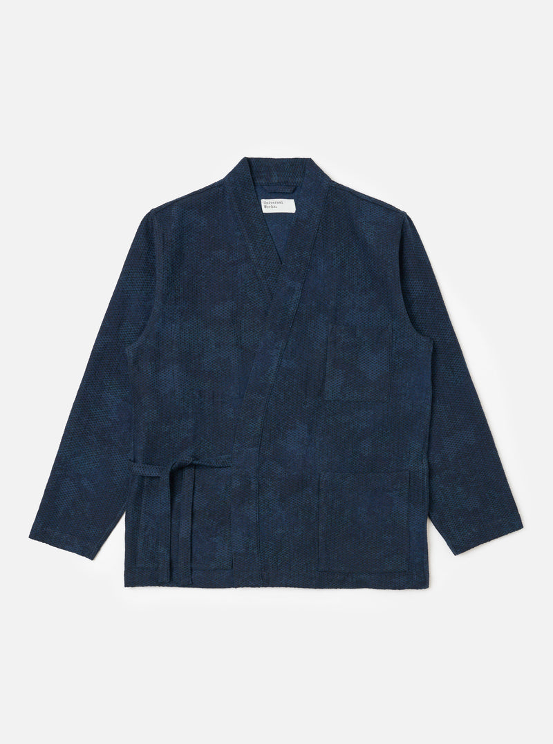 The Black/Indigo Denim Camo Kyoto Work Jacket is displayed on a white background. The jacket is a dark indigo color with a subtle camo pattern. It has a relaxed fit and a workwear-inspired design.