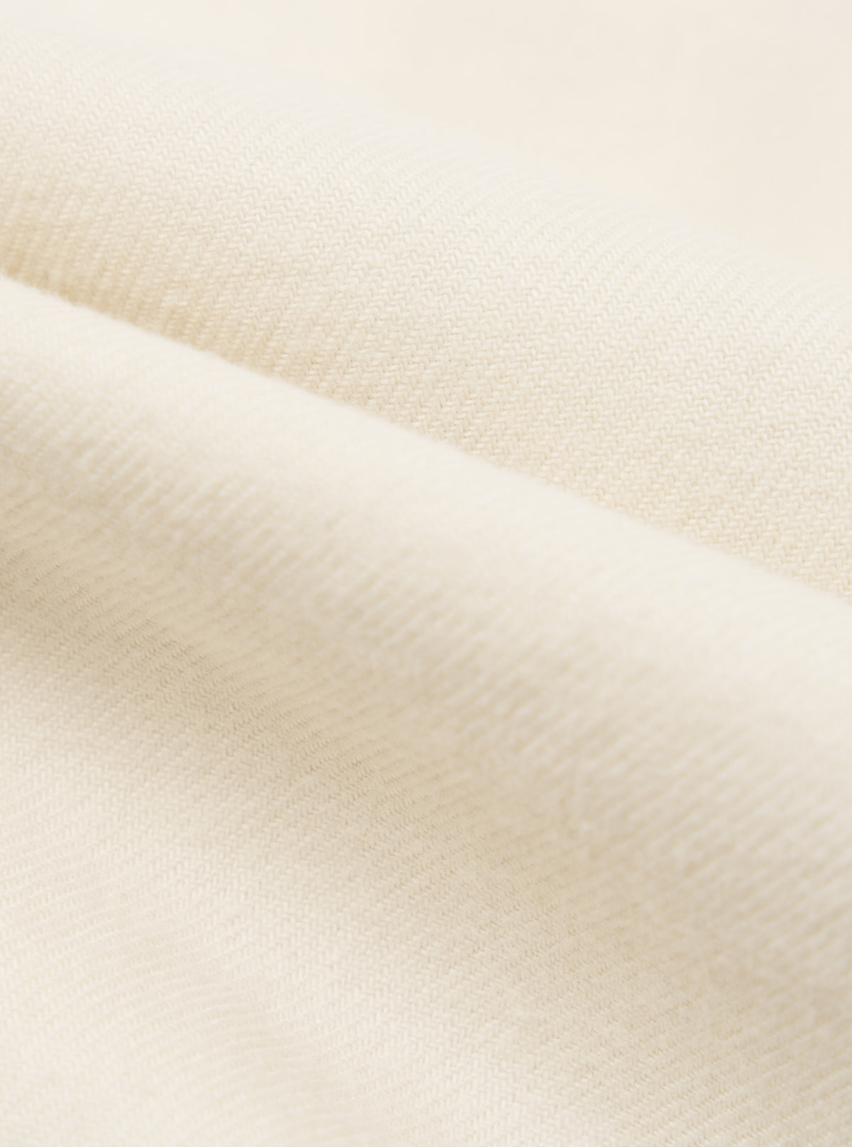 Close-up of the Ecru Sid Flannel CPO Shirt fabric. Soft, ecru-colored flannel material is folded to show texture. Studio shot.