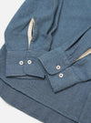 Close-up of the Blue Brushed Marl Twill Square Pocket Shirt on a white surface. Shows the blue twill fabric, buttoned cuffs, and contrasting trim.