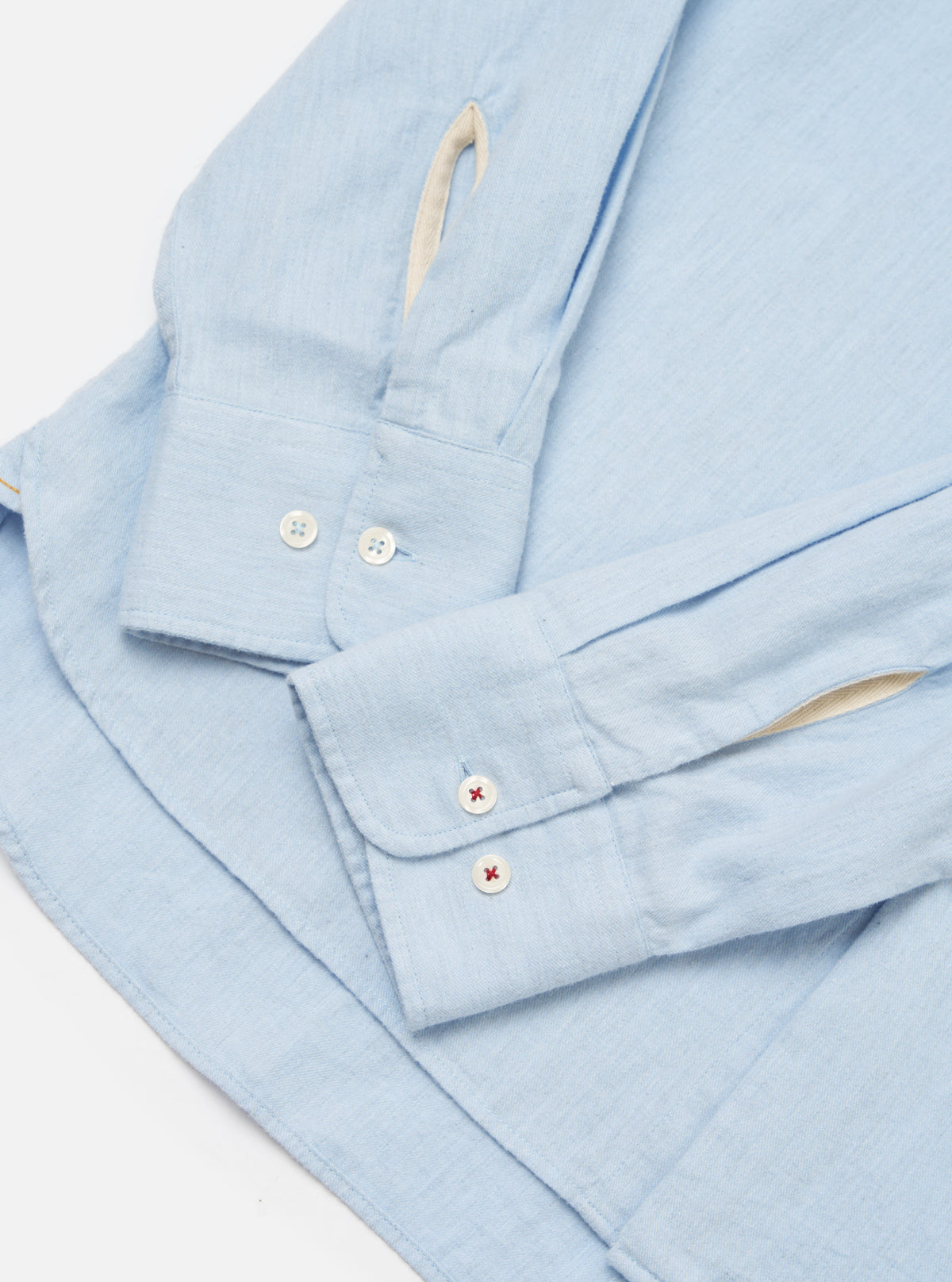 Close-up of the Light Blue Brushed Marl Twill Square Pocket Shirt on a white surface. Shows the sleeve and cuff detail with buttons.