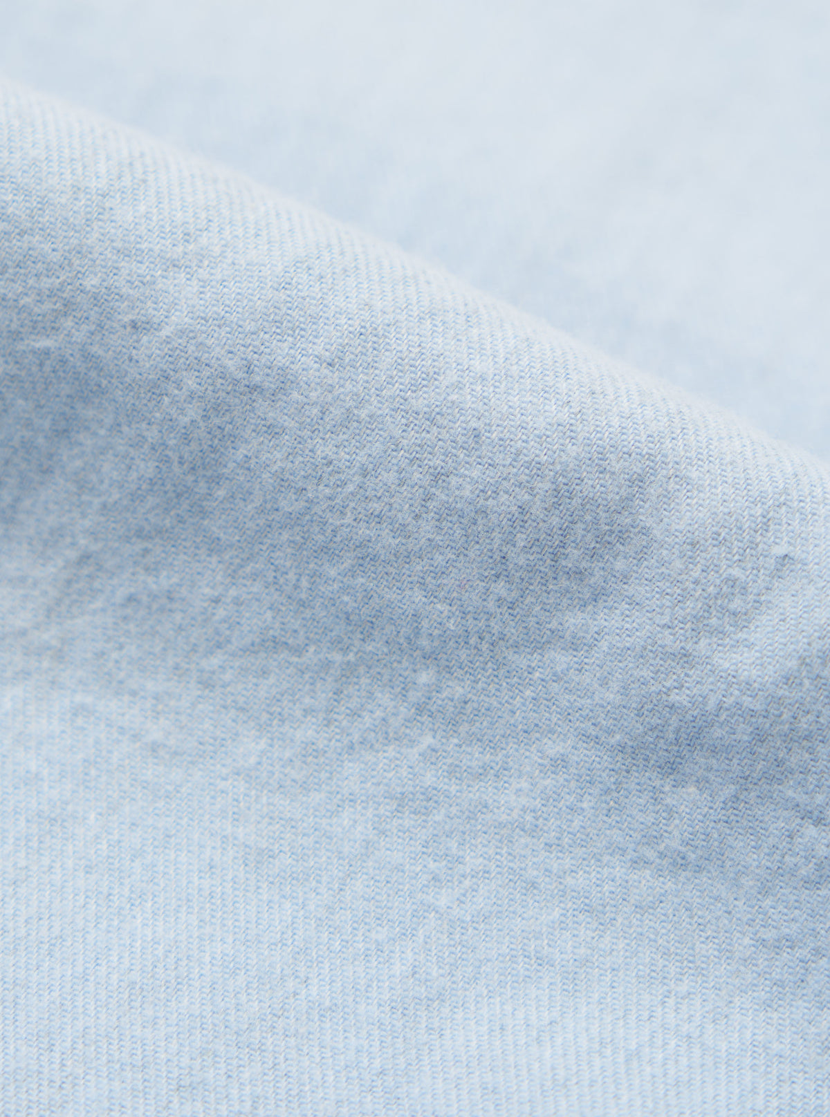Close-up of the light blue brushed marl twill fabric of the square pocket shirt. The soft texture and subtle pattern are visible against a plain background.