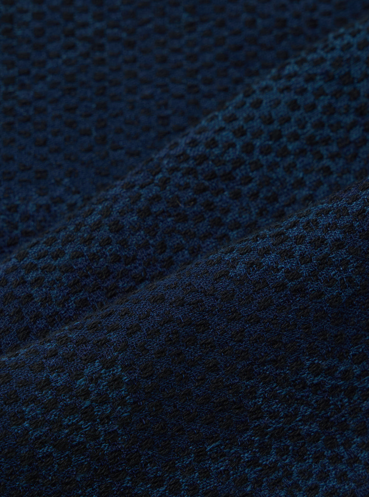 Close-up of the Black/Indigo Denim Camo Pleated Track Pant fabric. The material is a textured blend of black and indigo, creating a subtle camo effect. 