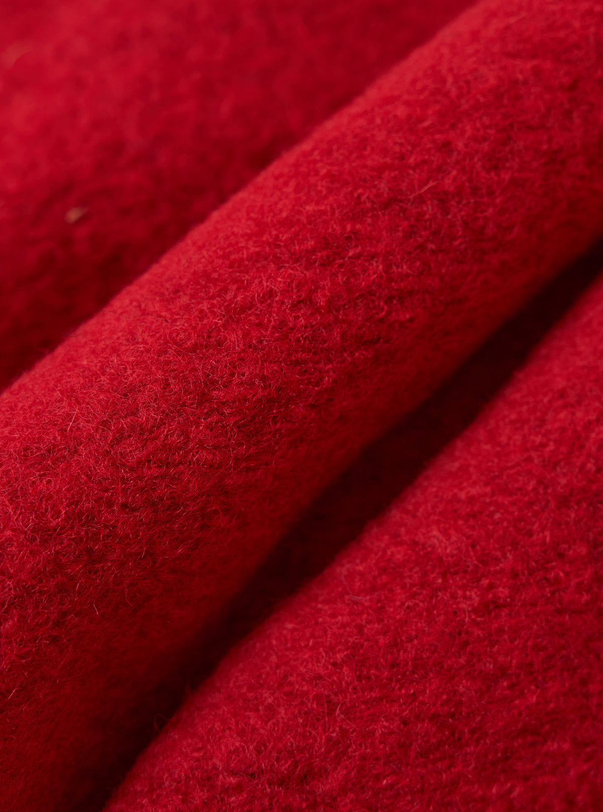 Close-up of the Red Wool Fleece Rams Jacket. The bright red wool material is folded, showing the texture of the fleece. 