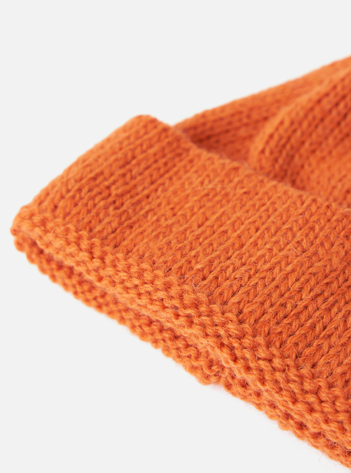 Close up of the Orange Alpaca/British Wool Bobble Hat on a plain white background. The wool is knitted and the hat is folded at the brim.
