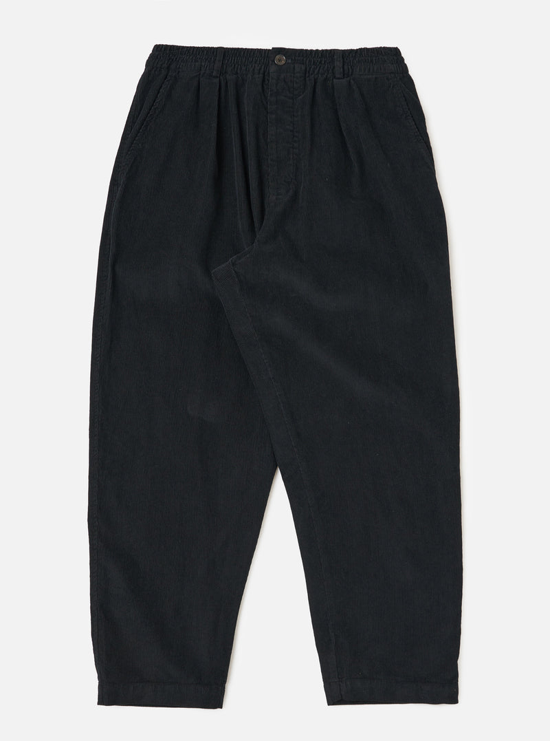 Studio shot of the Black Cat Cord Pleated Track Pant. The black corduroy pants are on a white background. The pants have a relaxed fit.