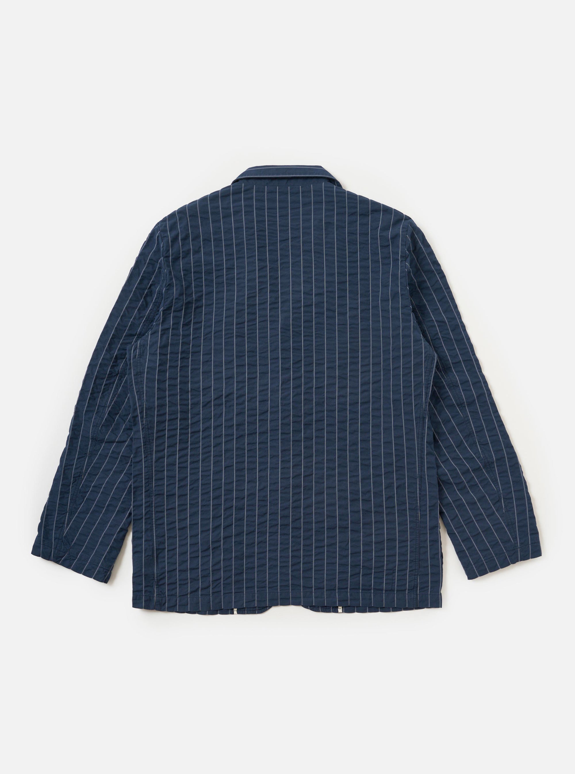 The Navy Chester Stripe Two Button Jacket is shown from the back, laid flat against a solid white background. The image highlights the vertical white pinstripe pattern on the navy blue cotton fabric, the structured shoulders, and the clean hemline.