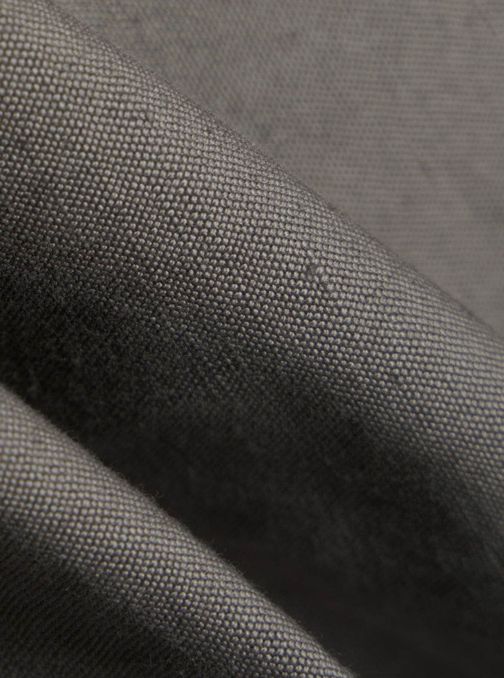 A close-up fabric swatch of the Mid Grey Linen Slub Weave E130 Jacket highlights the textured, slubbed appearance of the linen and cotton blend. The image focuses on the weave and the mid-grey color of the material.