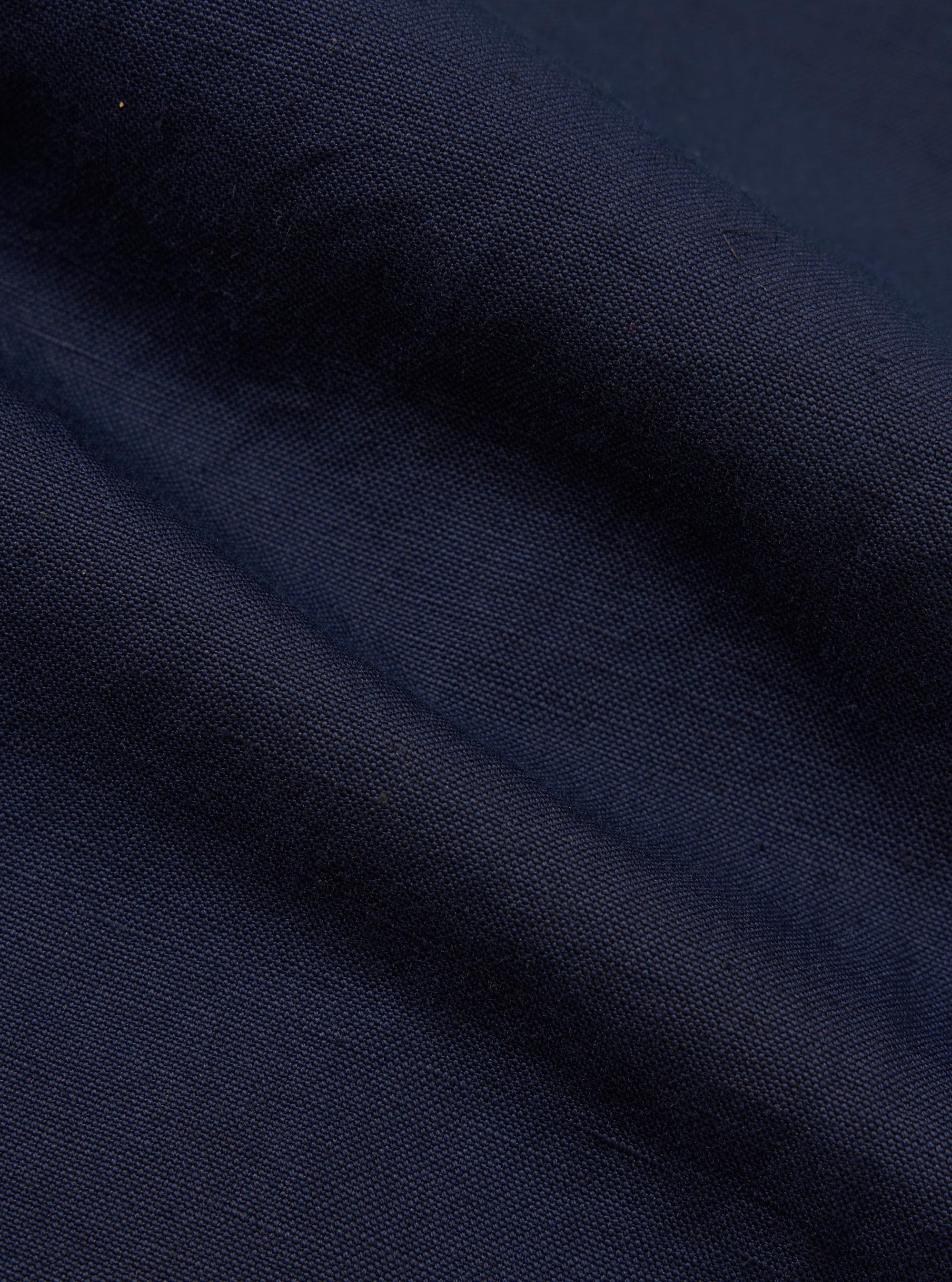 A close-up fabric swatch of the Navy Linen Slub Weave Two Button Jacket shows a detailed view of the textured, navy blue material. The image highlights the irregular slubby yarns and the character of the linen-cotton blend weave.
