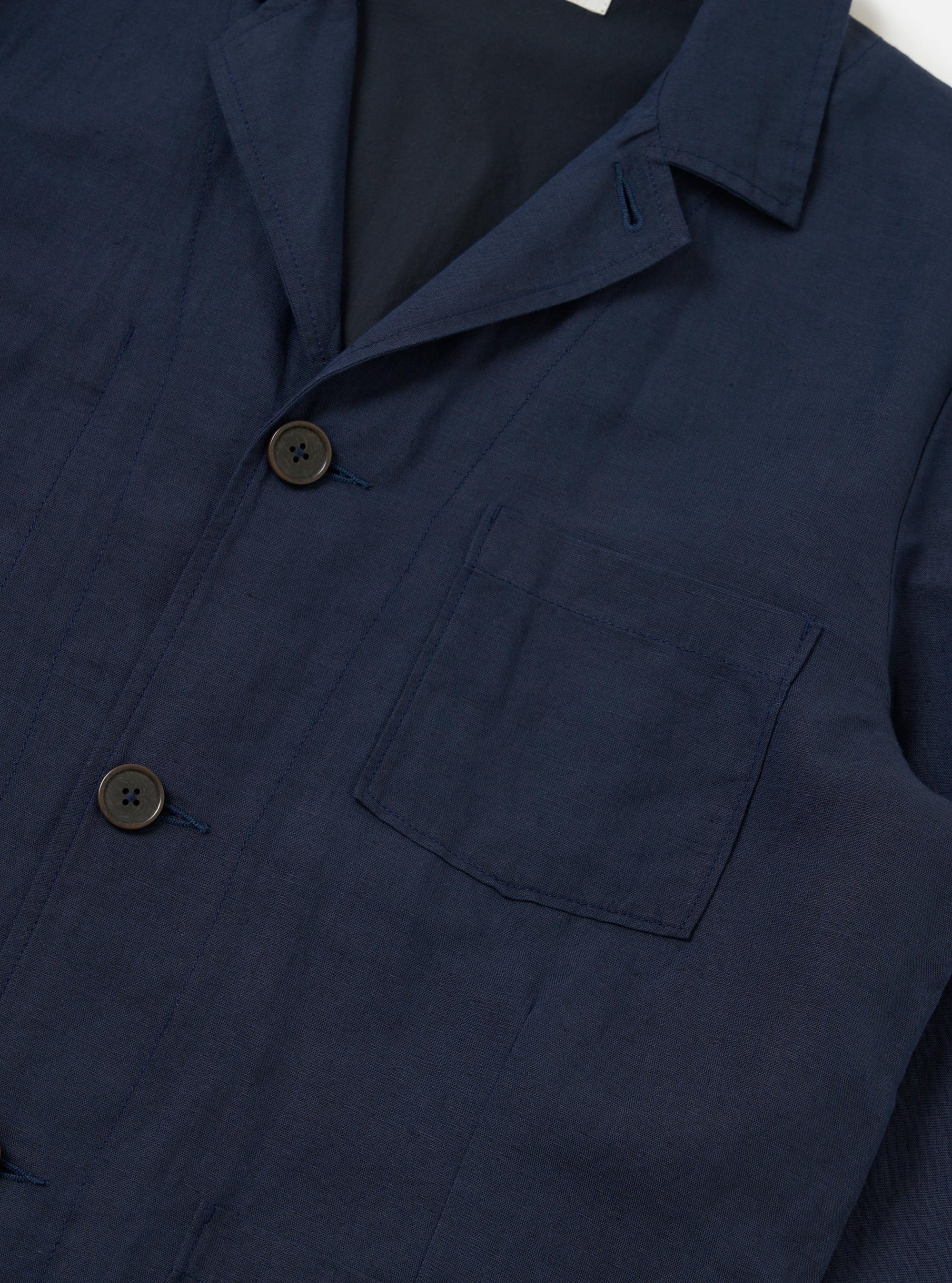 The Navy Linen Cotton Shirting Dizzy Jacket is shown from a rear perspective, laid flat against a solid white background. The image highlights the clean construction of the back, the simple collar, and the straight-cut hem of the garment.