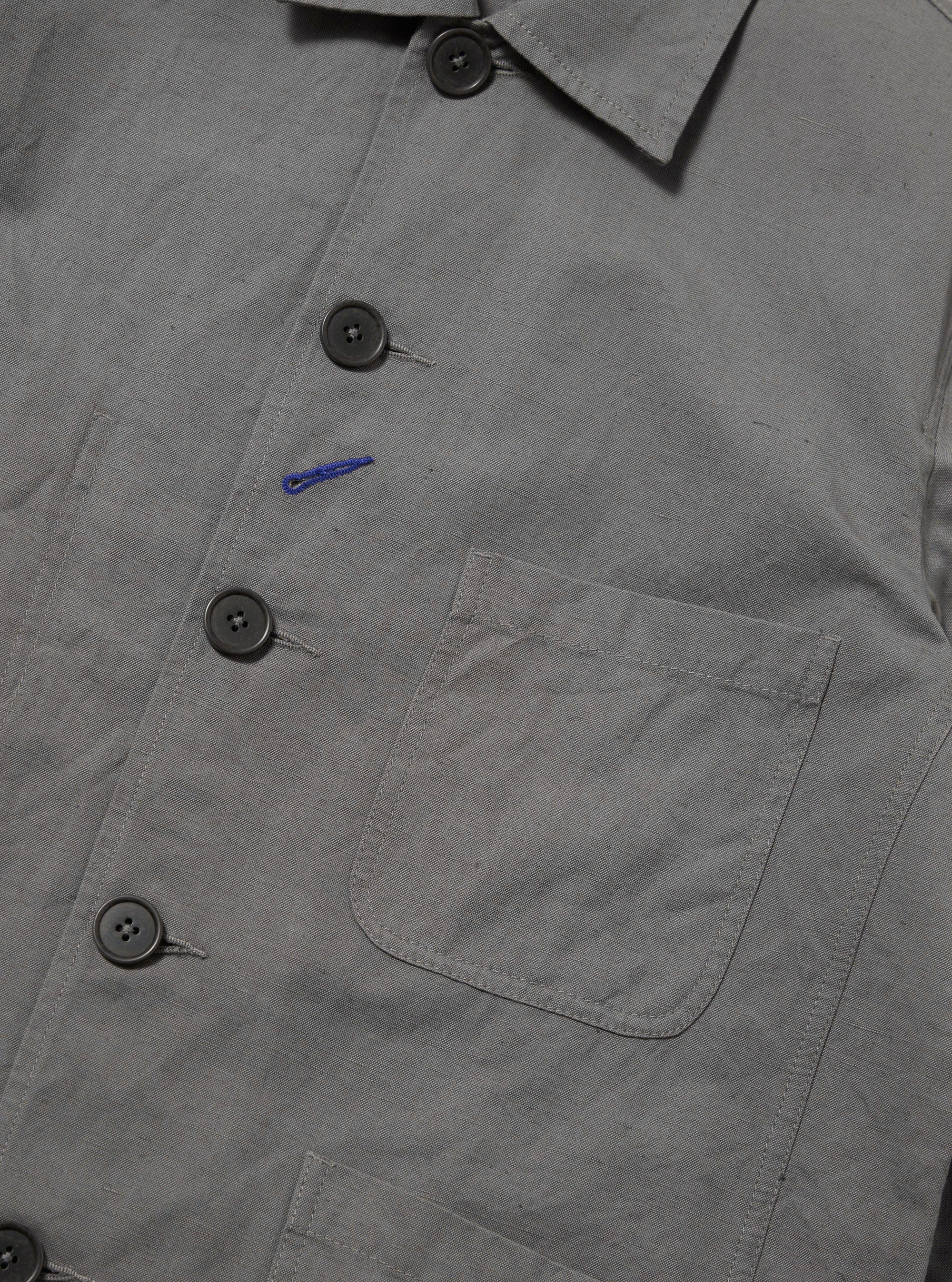 The Mid Grey Linen Slub Weave Bakers Jacket is shown from the back, laid flat against a plain white background. The image highlights the jacket's structured collar, straight hem, and central back seam, showcasing the textured slub weave of the mid-grey linen-cotton fabric.