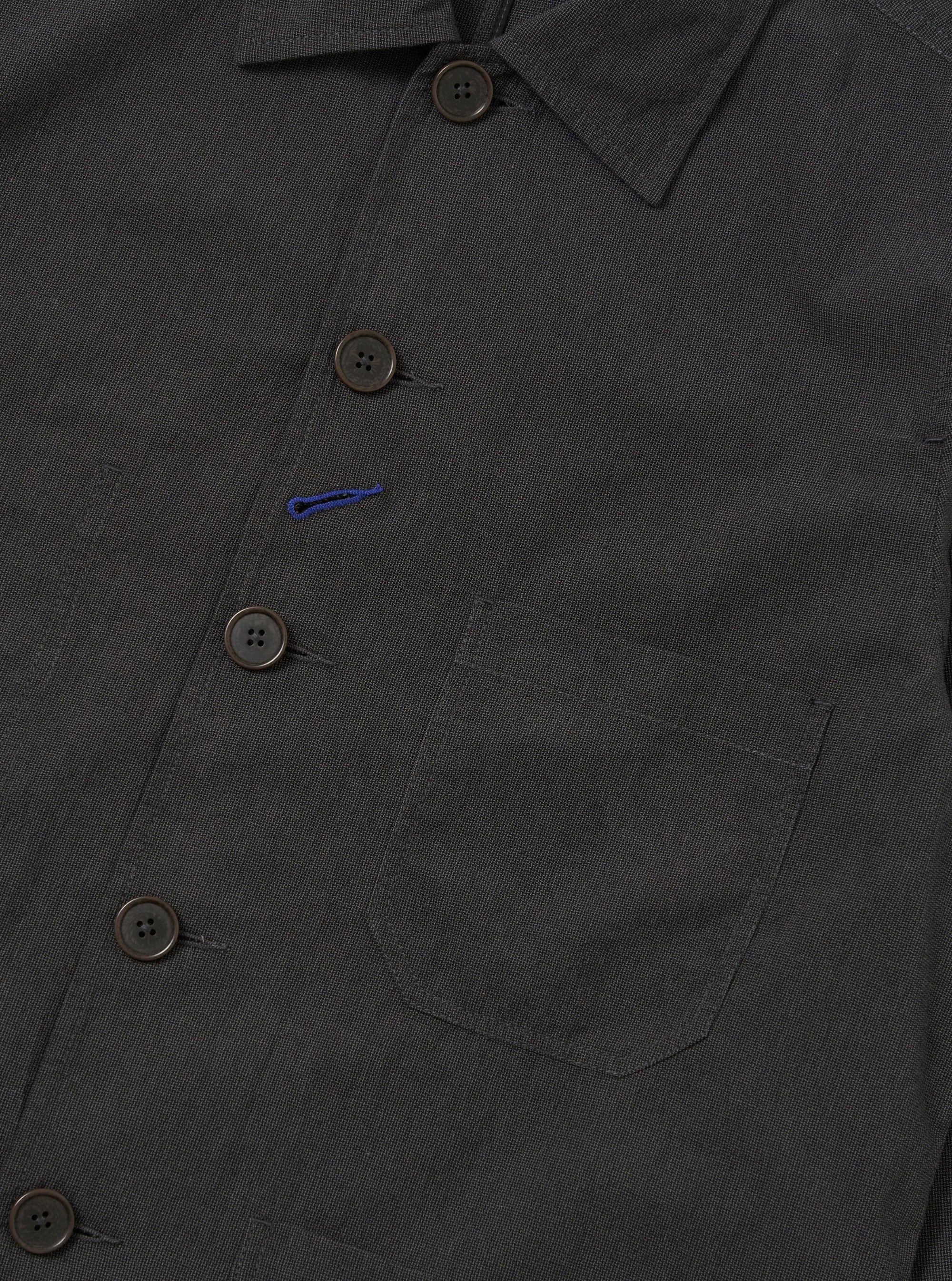 A Charcoal Seattle Cotton OG Bakers Jacket is shown from the back, laid flat against a solid white background. The image highlights the simple, clean construction of the rear, featuring a straight hem and the textured charcoal grey cotton fabric.