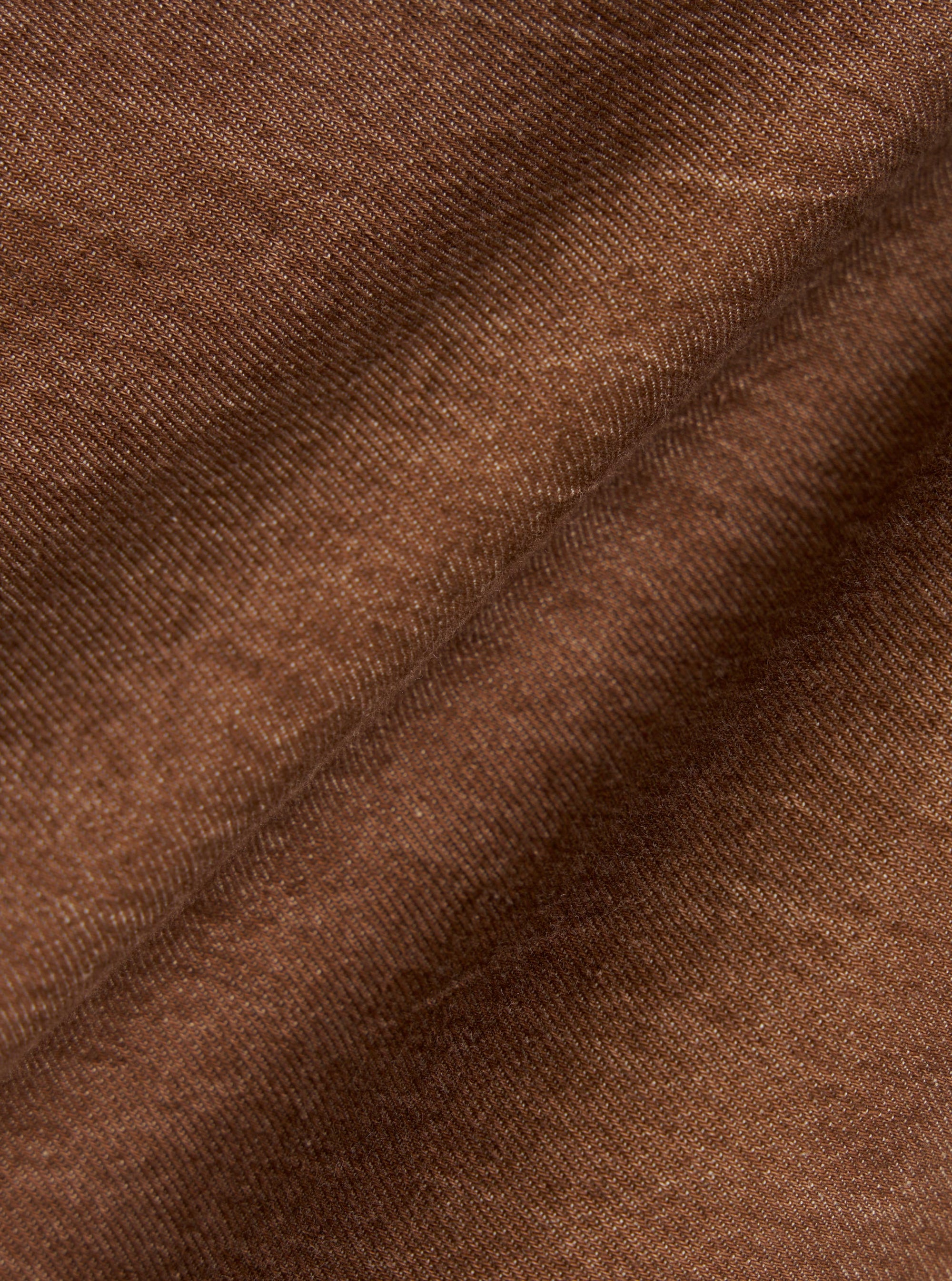 A close-up fabric swatch of the brown Meco denim used for the OG Bakers Jacket shows a detailed view of the material's texture and earthy brown color. The image focuses entirely on the weave of the recycled cotton fabric.
