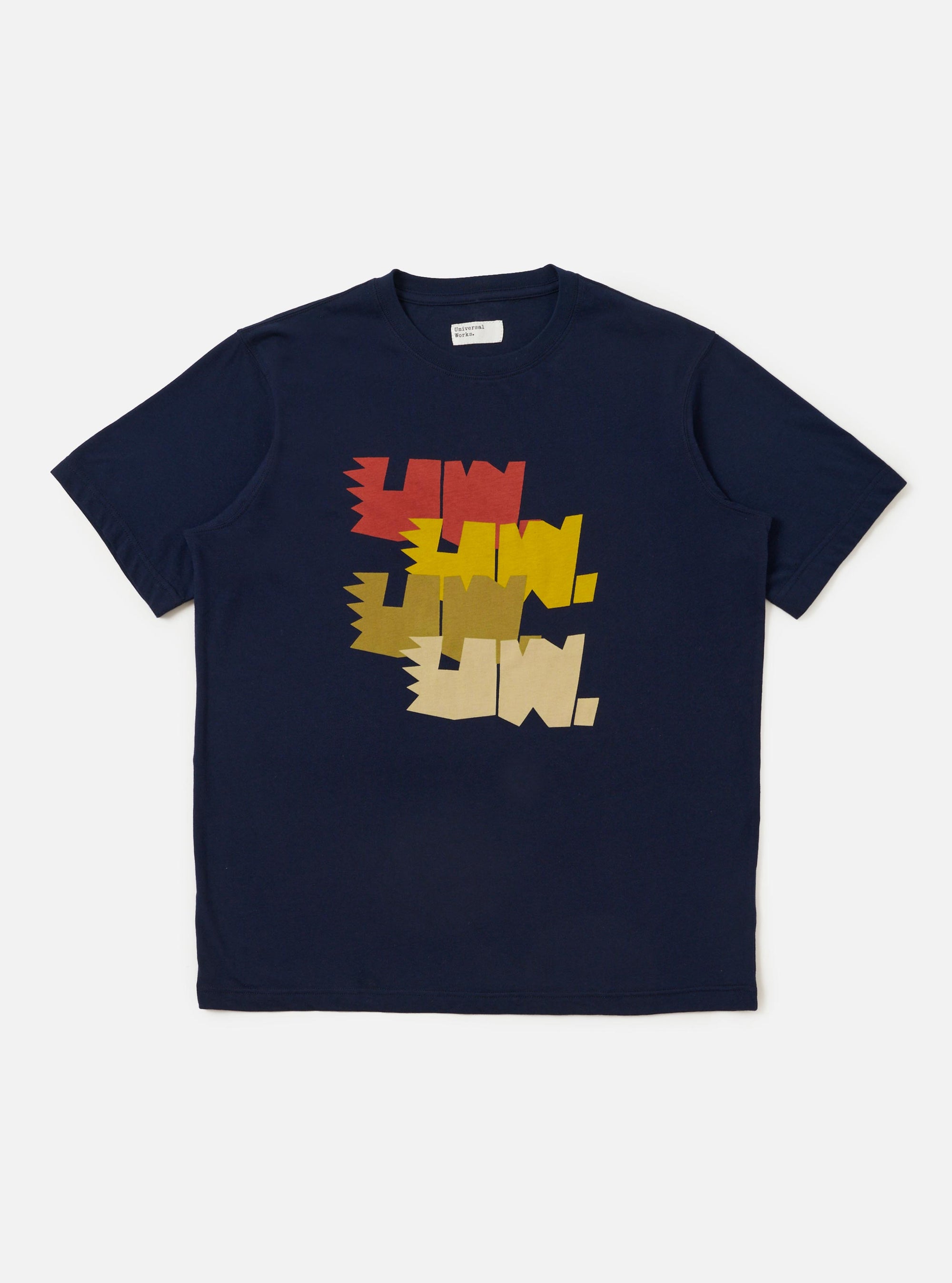 The Navy Single Jersey Multi UW Print Multi UW Print Tee is shown laid flat against a solid white background. The navy blue t-shirt features a repeat white graphic print of the Universal Works logo across the entire garment. It has a classic crew neckline and short sleeves.