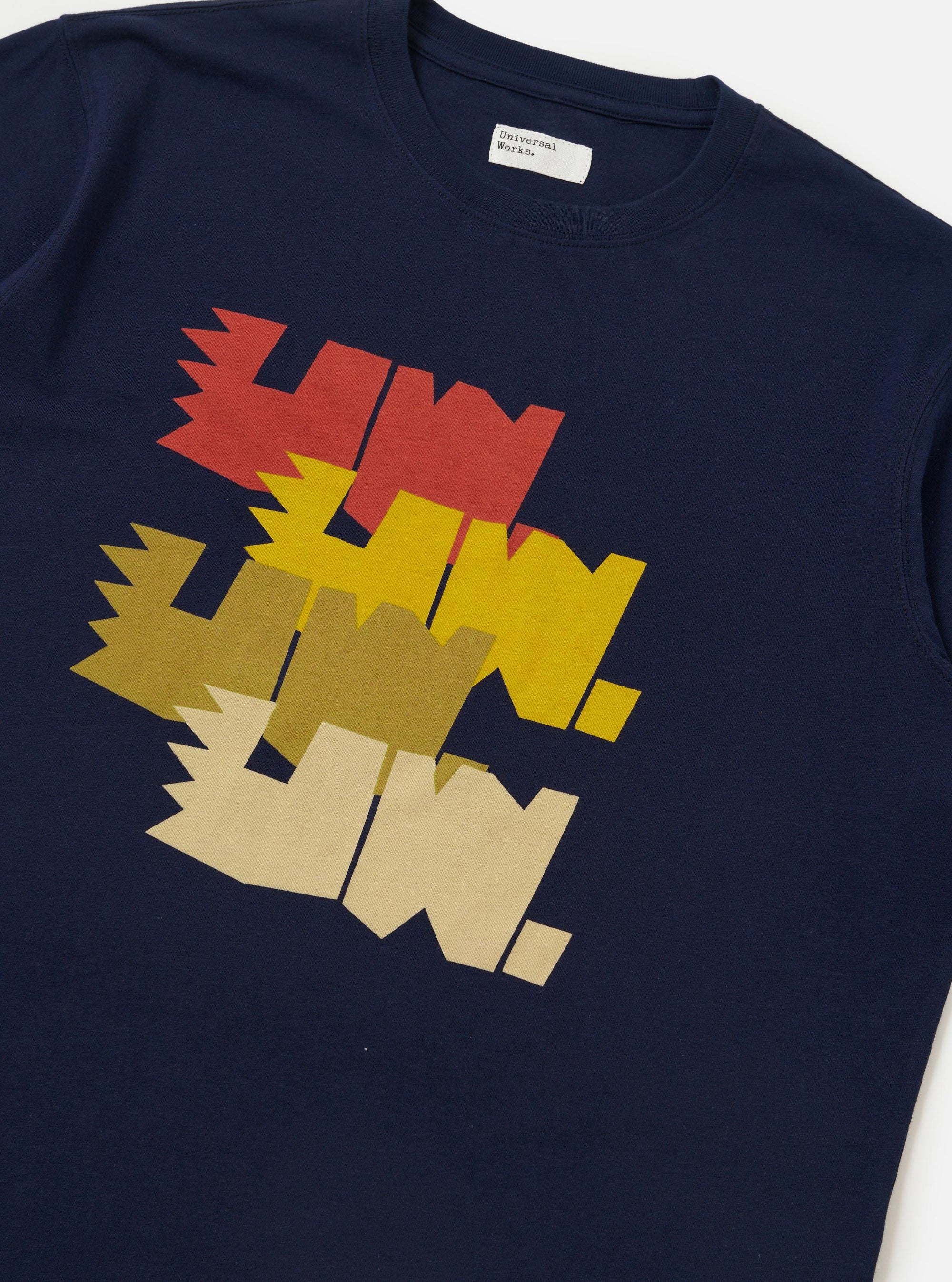 The Navy Single Jersey Multi UW Print Multi UW Print Tee is shown from a rear perspective, laid flat against a solid white background. The image highlights the straight hem, short sleeves, and the continuation of the white "UW" logo print across the back of the navy blue cotton fabric.