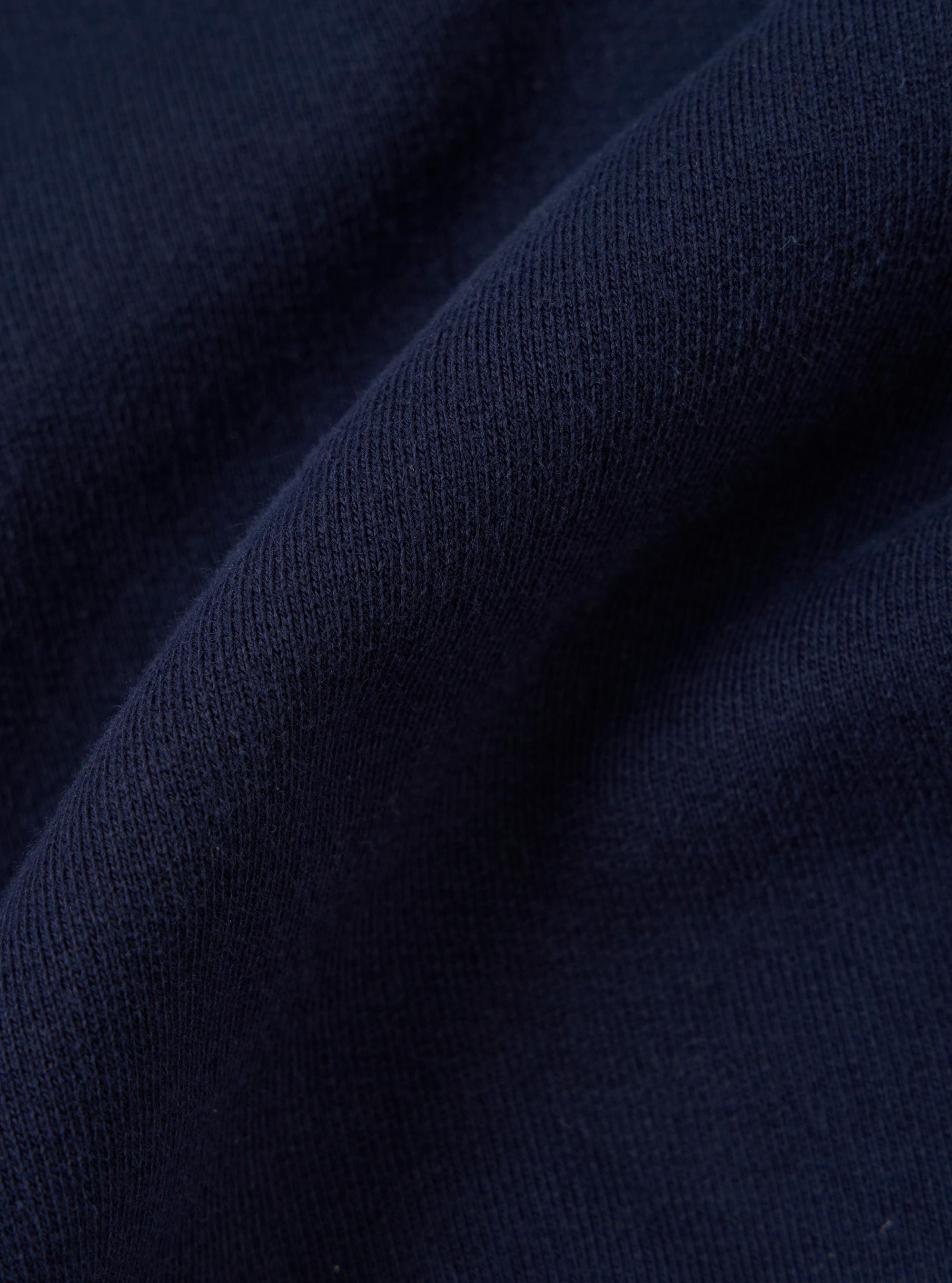 A close-up, square fabric swatch of the Navy Brush Back Sweat FM Raglan Sweatshirt highlights the textured, navy blue cotton material. The image focuses on the fine, soft-brushed surface and tight knit of the fabric.