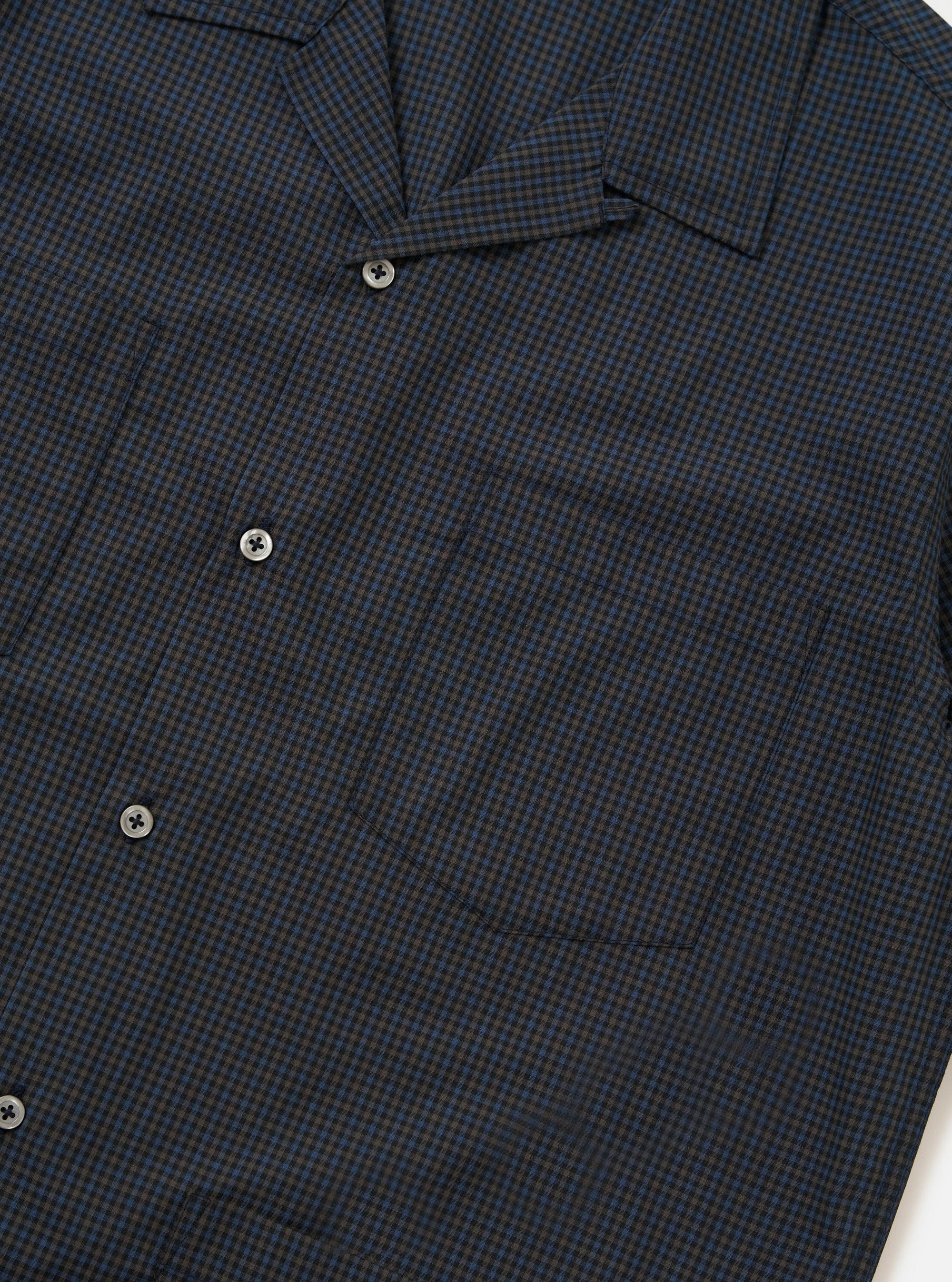 The Navy Check Plaid Summer Overshirt is shown from the back, laid flat against a solid white background. The image highlights the back yoke and the clean, straight hem of the garment, showcasing the dark navy and white plaid pattern.