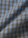 A square fabric swatch shows a detailed close-up of the Pale Blue Check Plaid Lazy Day Shirt. The pattern consists of a multi-colored plaid in shades of pale blue, navy, white, and tan. The fabric texture is visible, and the image is set against a neutral, out-of-focus background.