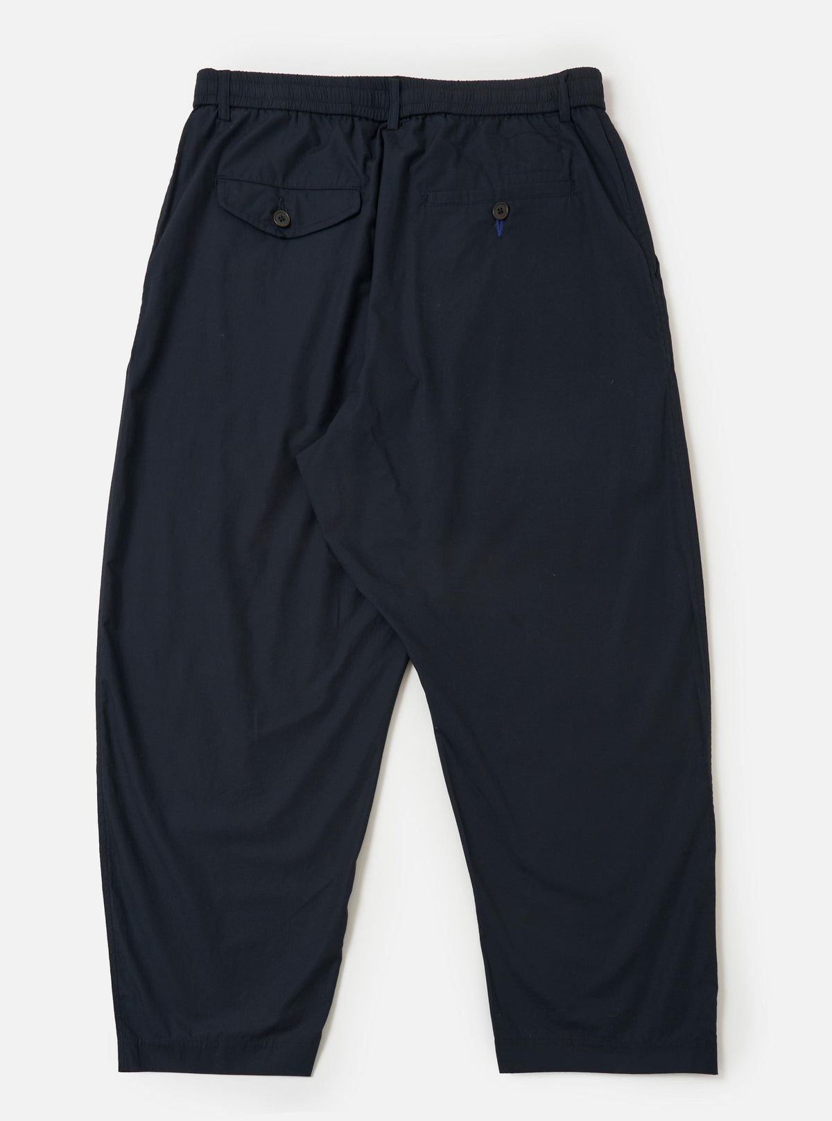 A pair of Navy Broadcloth Oxford Pants is shown from the back, laid flat against a plain white background. The navy blue trousers feature a wide-leg silhouette and a clean waistband with a single rear buttoned pocket.