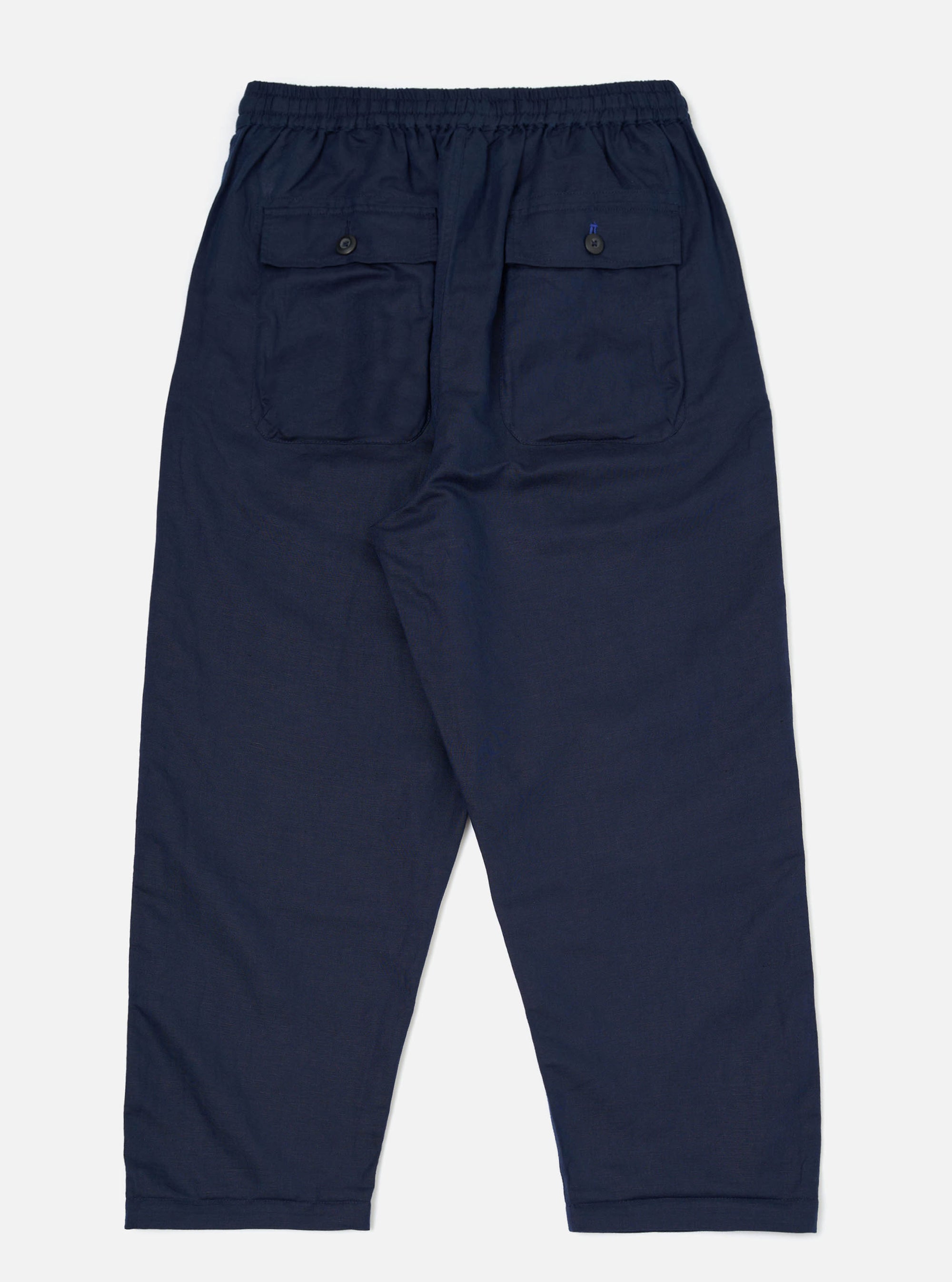 A pair of Navy Linen Cotton Shirting Parachute Pants is shown from the back, laid flat against a plain white background. The navy blue trousers feature a relaxed, straight-leg fit, a drawstring waistband, and two rear patch pockets.
