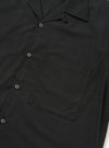 A Black Broadcloth Camp Shirt is displayed flat against a plain white background. The shirt features a classic camp collar, a full button-down front, and short sleeves. The fabric is a smooth black cotton broadcloth.