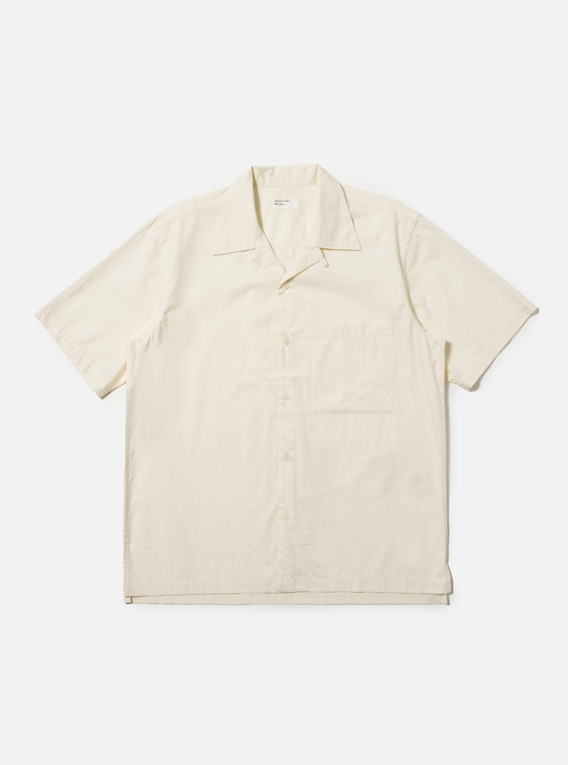 The Ecru Broadcloth Camp Shirt is shown laid flat against a solid white background. The shirt features a relaxed fit, short sleeves, and a classic one-piece camp collar. A single large square chest pocket is visible on the left side, and the front has a tonal button closure.