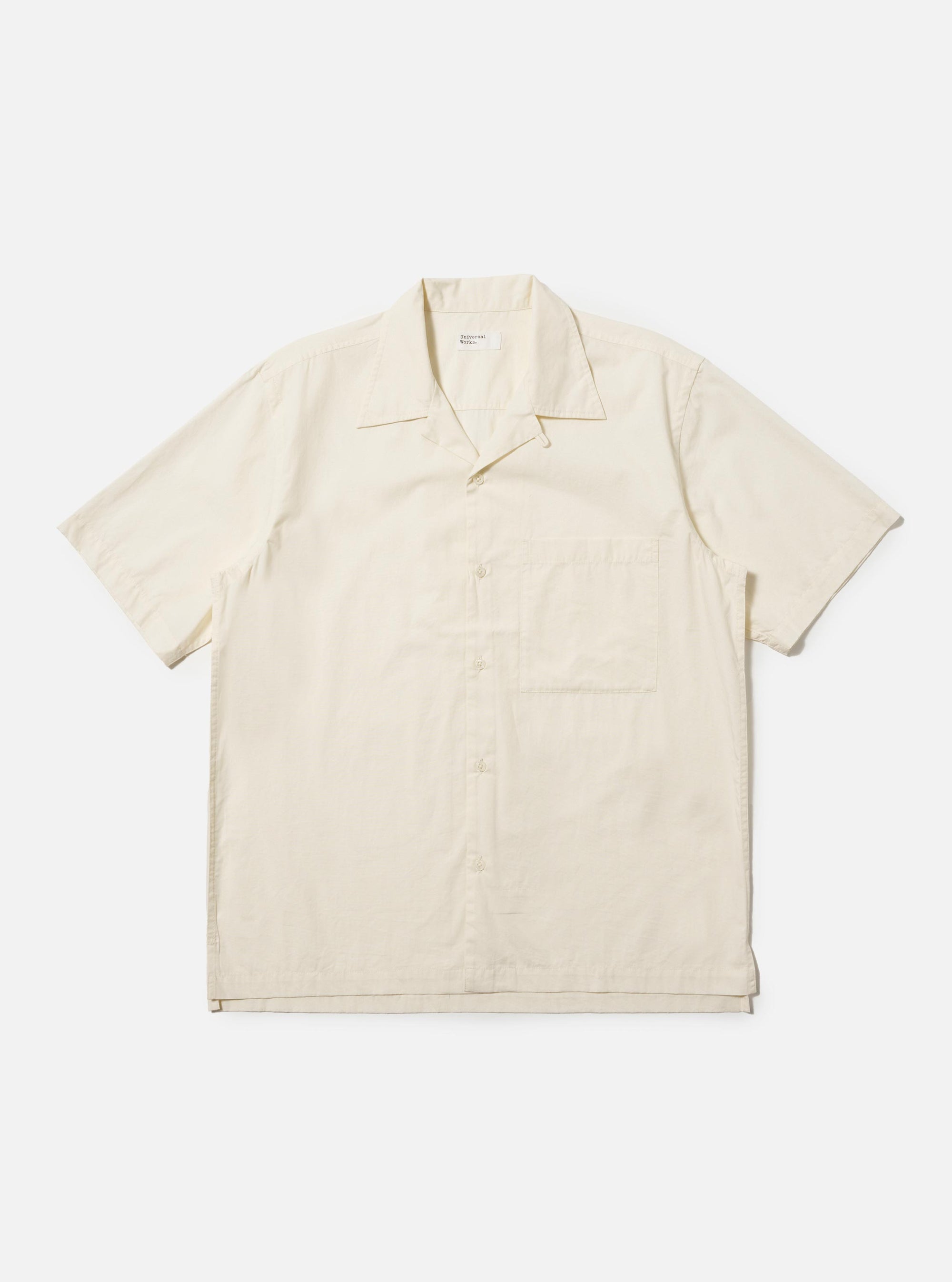 The Ecru Broadcloth Camp Shirt is shown laid flat against a solid white background. The shirt features a relaxed fit, short sleeves, and a classic one-piece camp collar. A single large square chest pocket is visible on the left side, and the front has a tonal button closure.