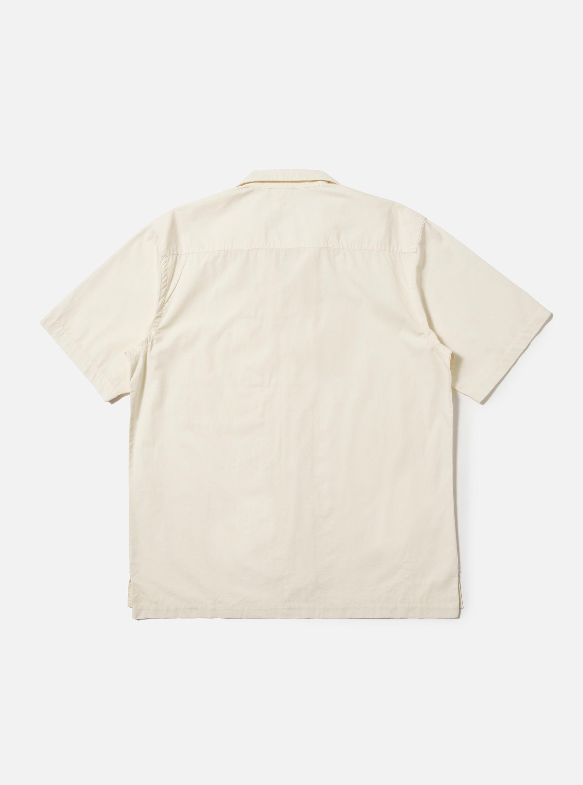The back of the Ecru Broadcloth Camp Shirt is shown laid flat against a plain white background. The short-sleeve shirt features a back yoke with small pleats for a relaxed fit and an elongated hem with side splits. The crisp, off-white cotton fabric is prominent throughout the garment.