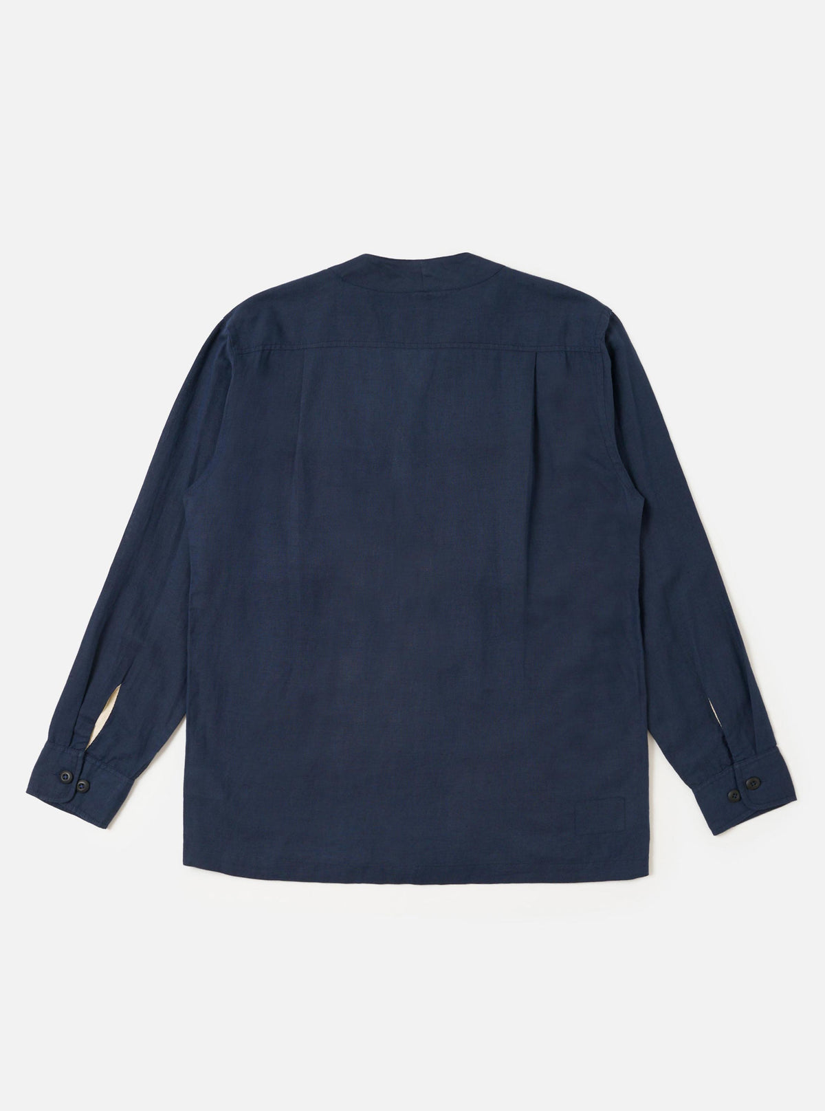 The Navy Linen Cotton Shirting Parachute Shirt is shown from the back, laid flat against a plain white background. The image highlights the horizontal back yoke with two small pleats and the adjustable buttoned cuffs on the long sleeves. The shirt features a straight hem and a collarless V-neckline.