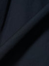 A close-up fabric swatch of the Navy Broadcloth Ewan Shirt highlights the smooth, tightly woven texture of the navy blue cotton material. The image focuses entirely on the fabric's fine grain and deep color.