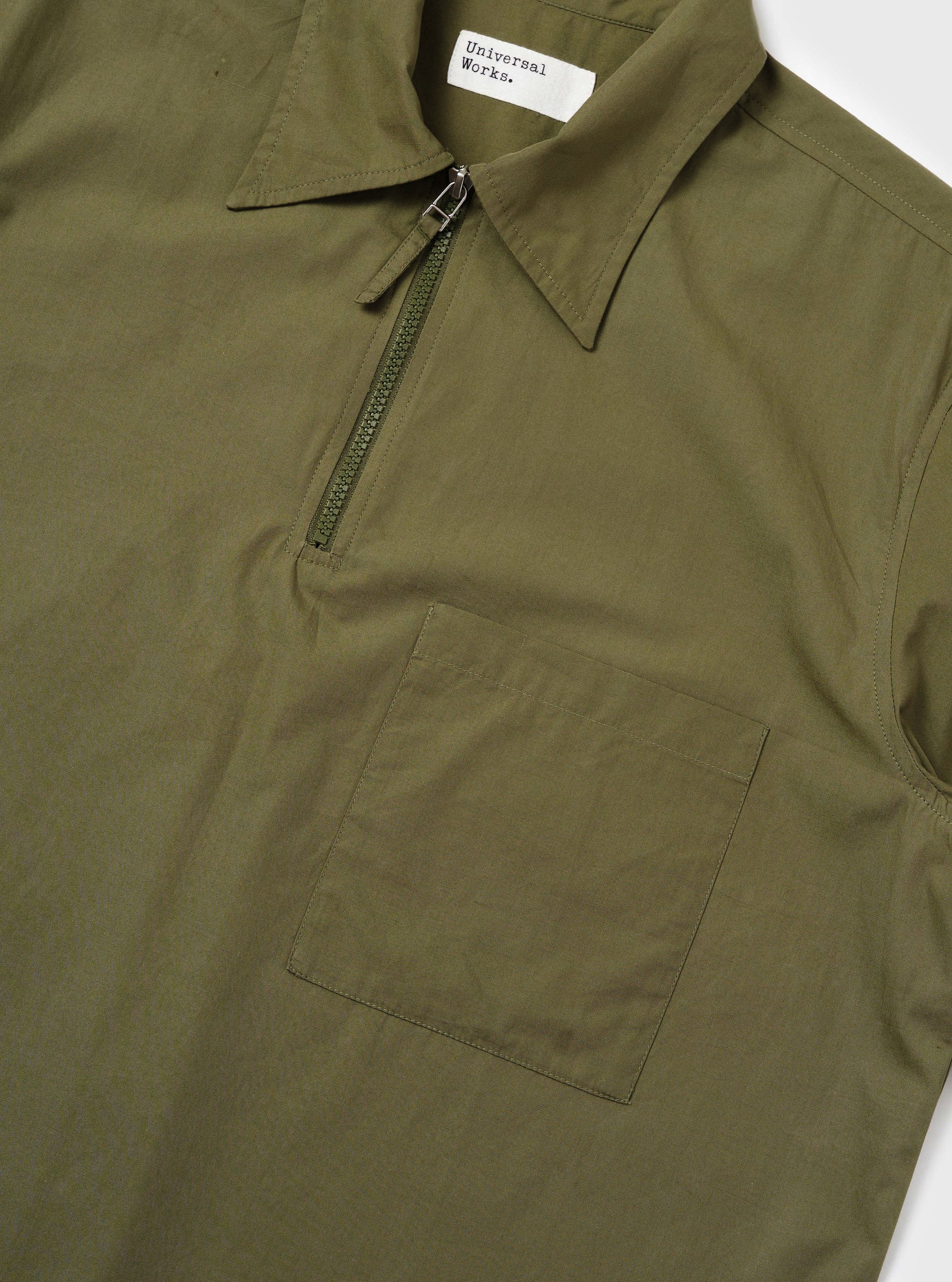 An Olive Broadcloth Ewan Shirt is shown from the back, displayed flat against a plain white background. The image highlights the short sleeves, a straight hem with side splits, and a horizontal back yoke with a central box pleat.