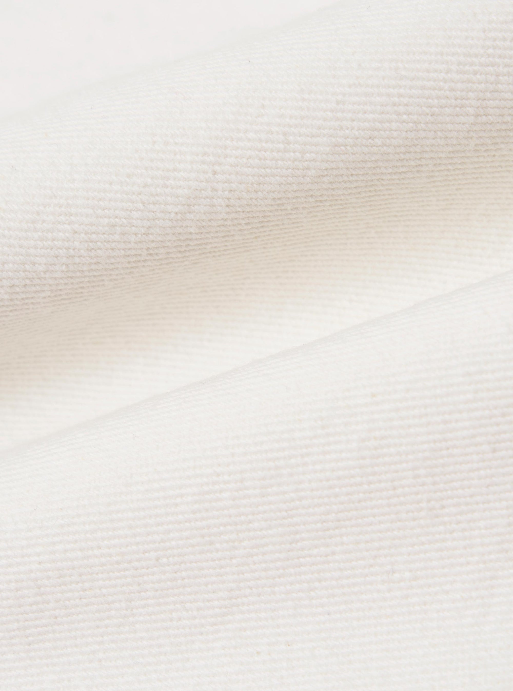 A close-up fabric swatch of the Ecru Slub Drill Dizzy Trouser displays the textured, off-white cotton material. The image highlights the characteristic slubby weave and durable drill construction of the fabric.