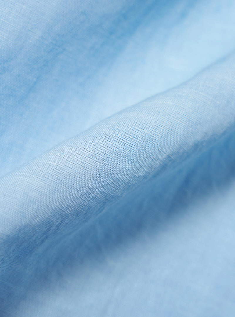 A detailed, close-up fabric swatch of the Pale Blue Linen Cotton Shirting Camp Shirt. The image highlights the textured, slubbed weave of the light blue material, showing the fine intersection of linen and cotton threads.