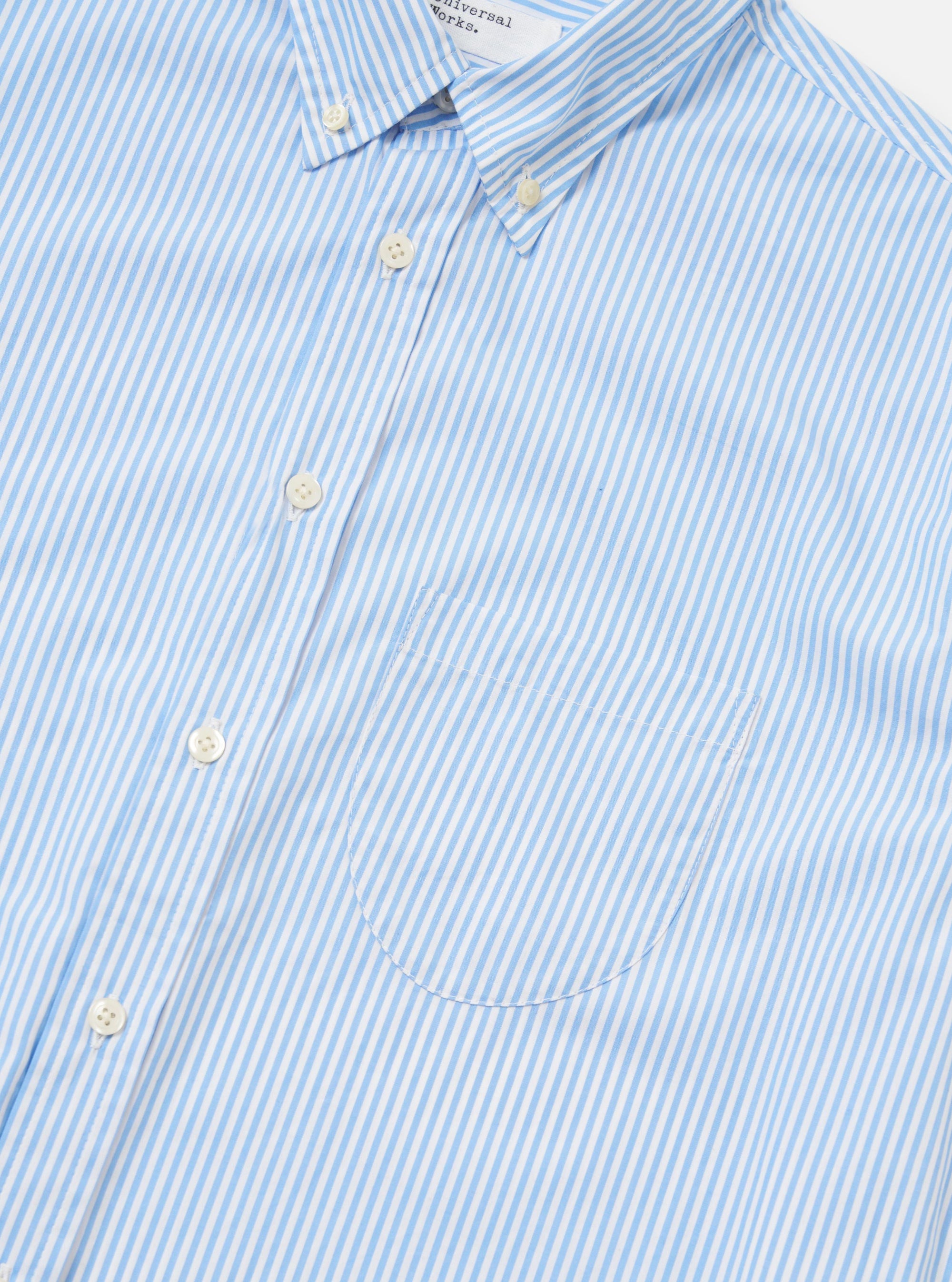 A detail shot of the Sky/White Classic Nipon Stripe Lazy Day Shirt is displayed against a plain white background. The image focuses on the upper portion of the shirt, highlighting the vertical blue and white stripes, the button-down collar, and the top buttons of the placket.