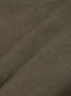 A detailed, close-up fabric swatch of the olive green linen-cotton shirting material used for the Bakers Overshirt. The image highlights the textured weave and solid color of the fabric.