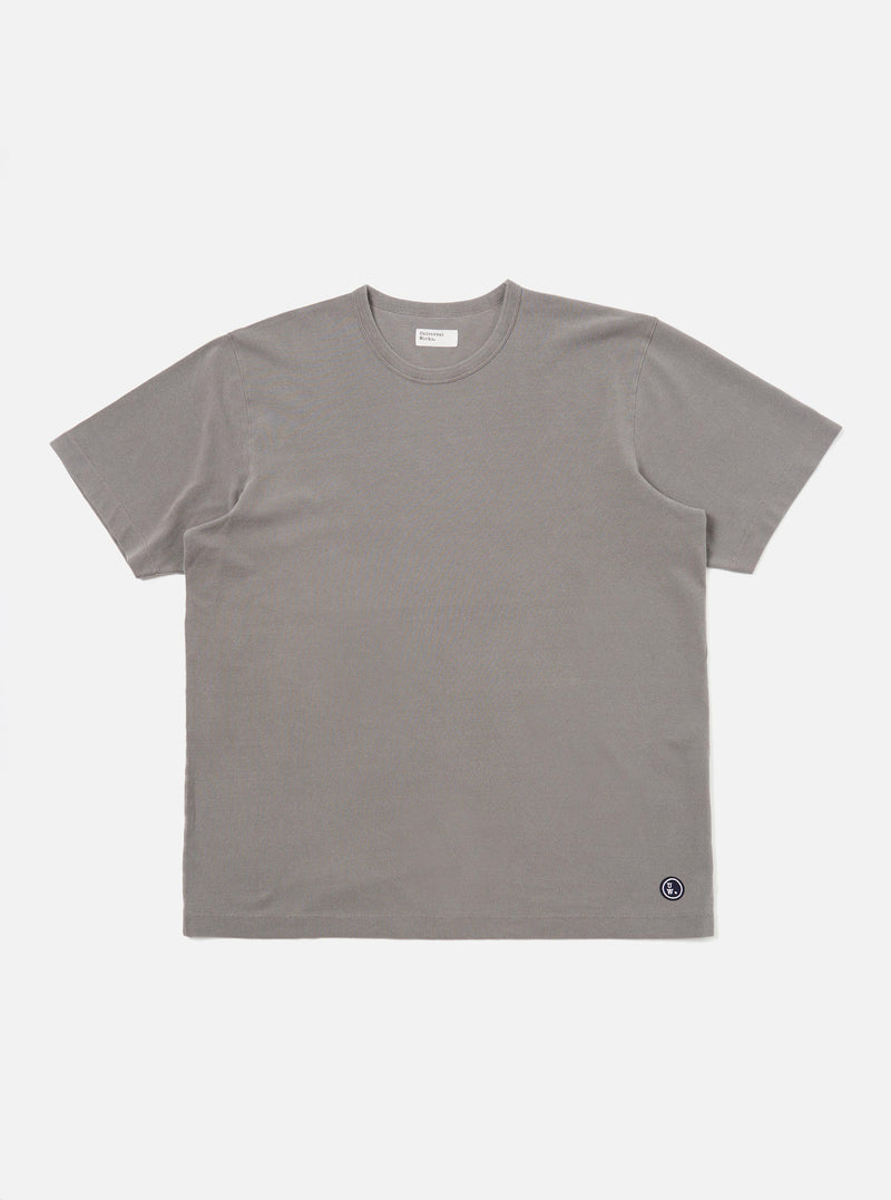 A mid-grey piquet core tee is shown laid flat against a solid white background. The short-sleeved t-shirt features a classic crew neck with a self-bound collar and a straight hem, highlighting the textured piquet cotton fabric.