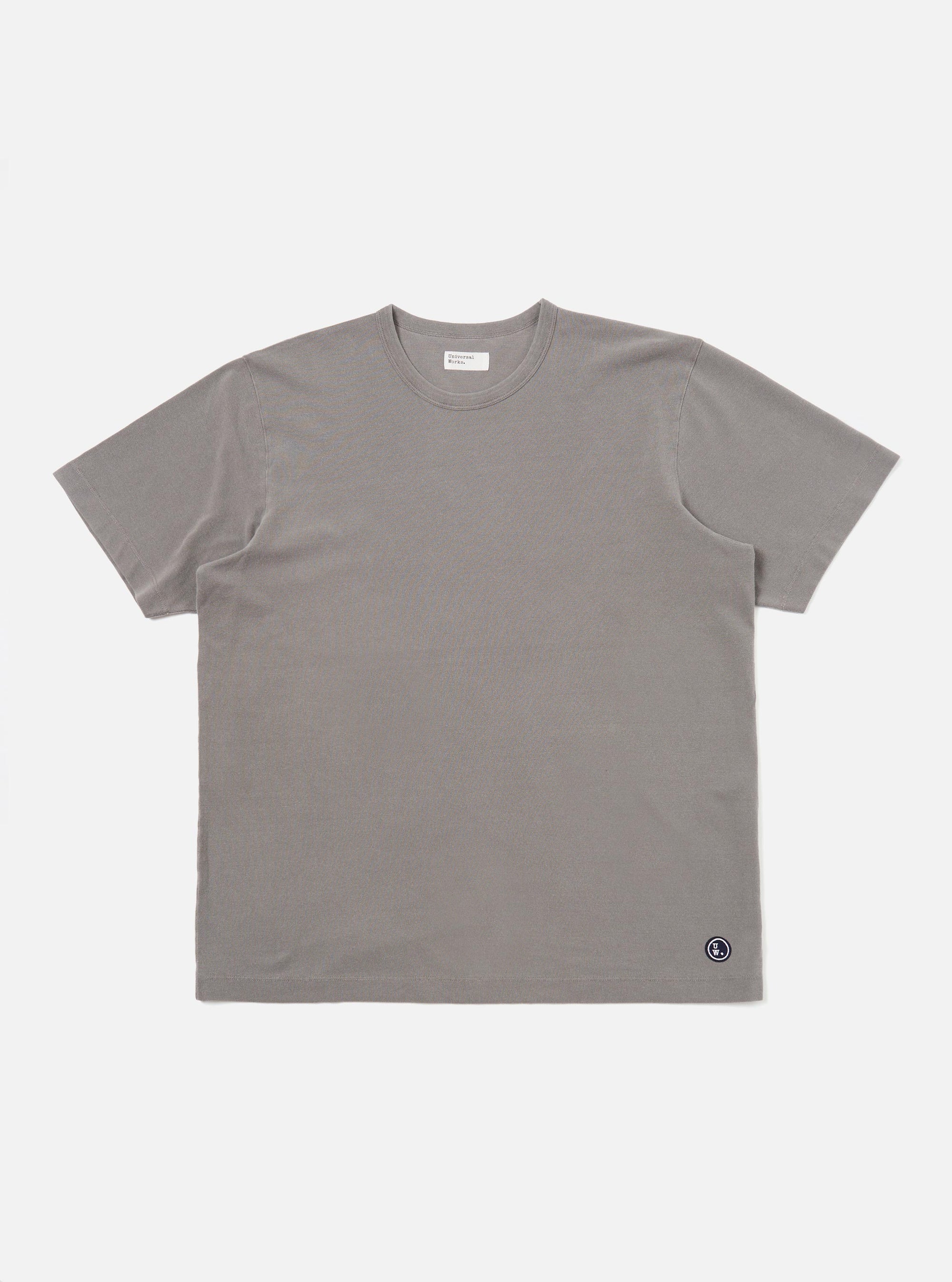 A mid-grey piquet core tee is shown laid flat against a solid white background. The short-sleeved t-shirt features a classic crew neck with a self-bound collar and a straight hem, highlighting the textured piquet cotton fabric.
