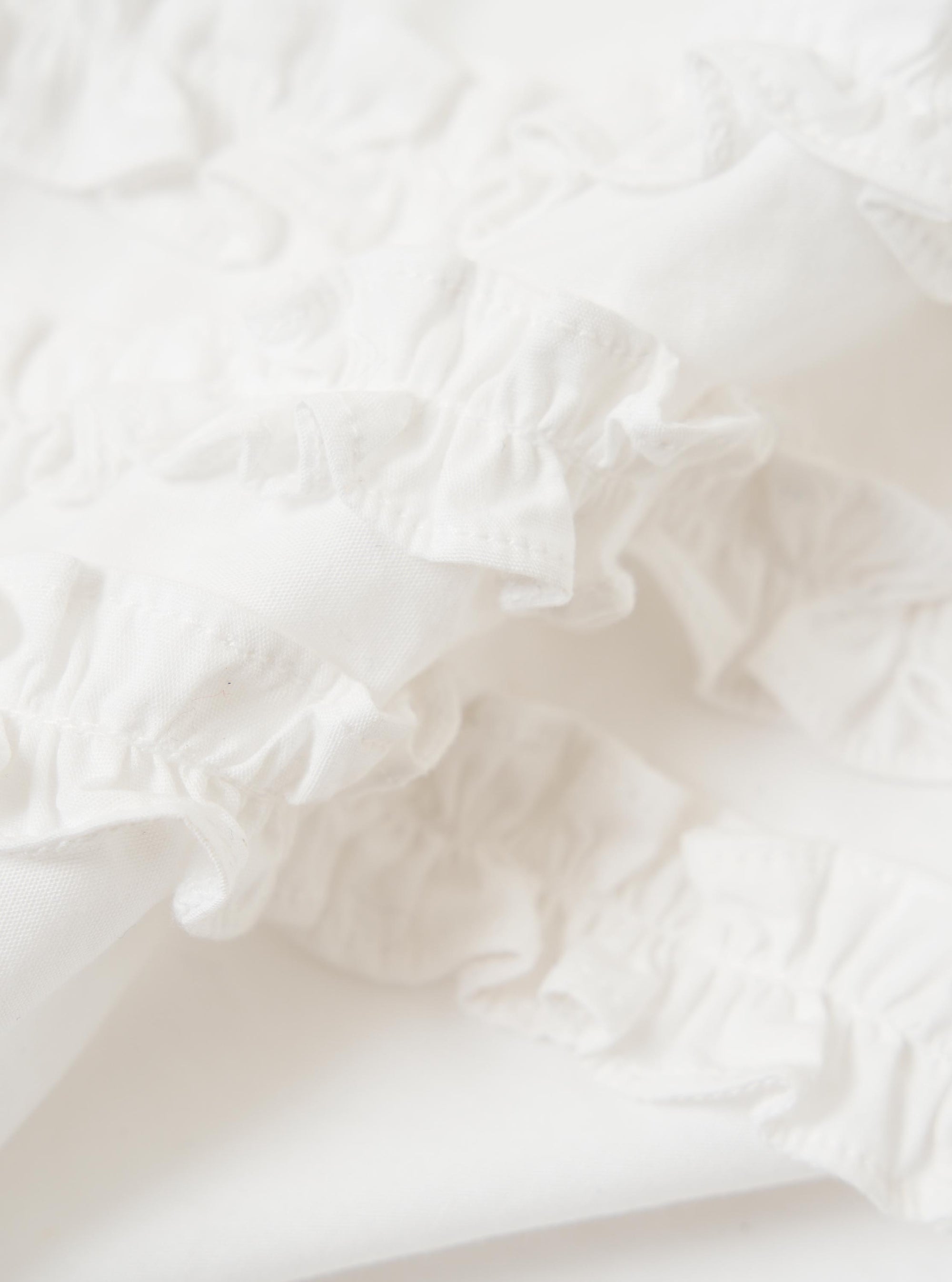 A close-up fabric swatch of the White Poplin Frill Shirt highlights the fine, smooth weave and crisp texture of the white cotton poplin material. The image focuses solely on the detail of the fabric against a neutral background.