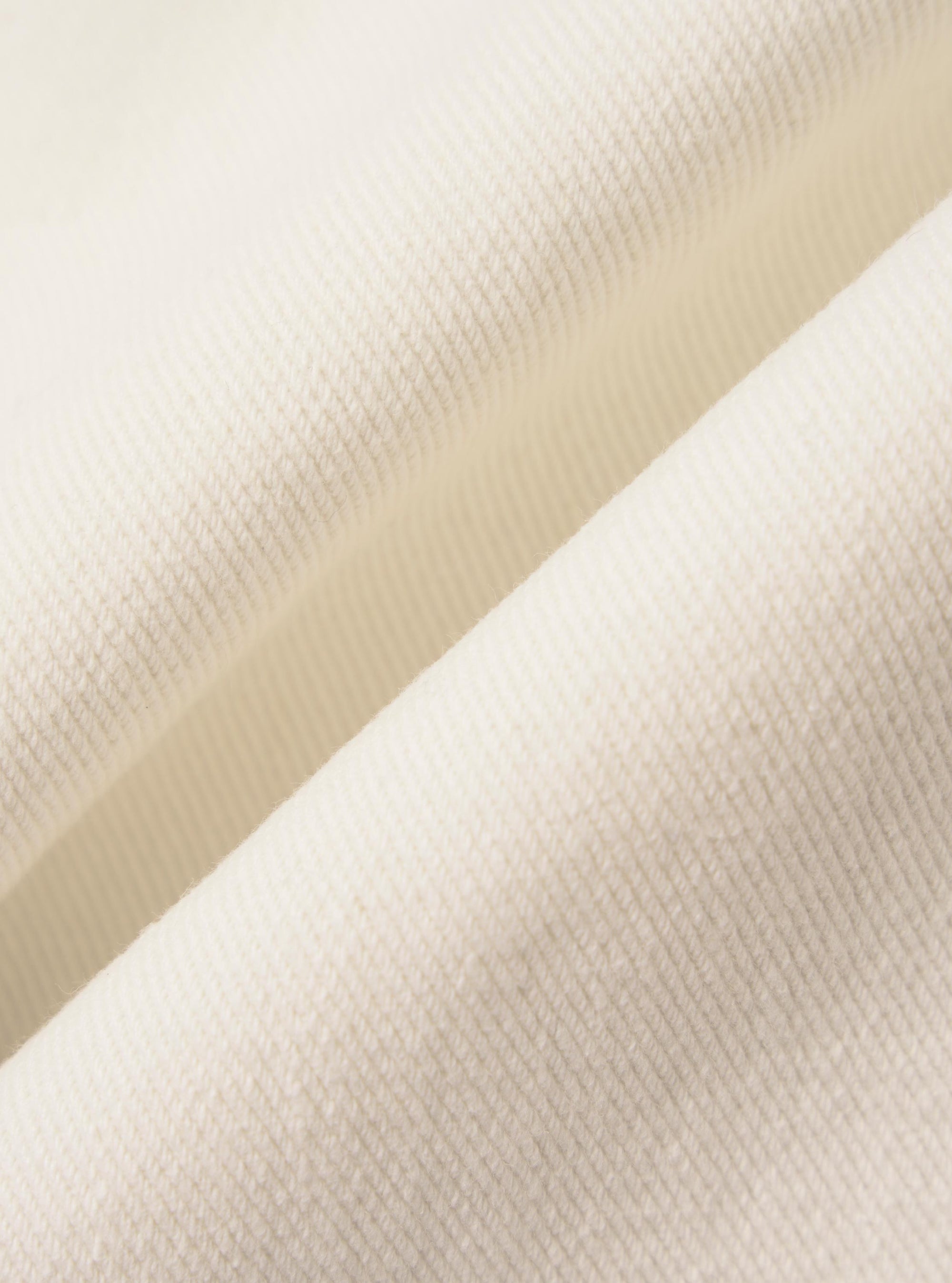 A detailed, close-up fabric swatch of the Ecru Slub Drill material used for the Dutch Pant. The image highlights the off-white, unbleached color and the distinct, textured slub weave of the cotton fabric.