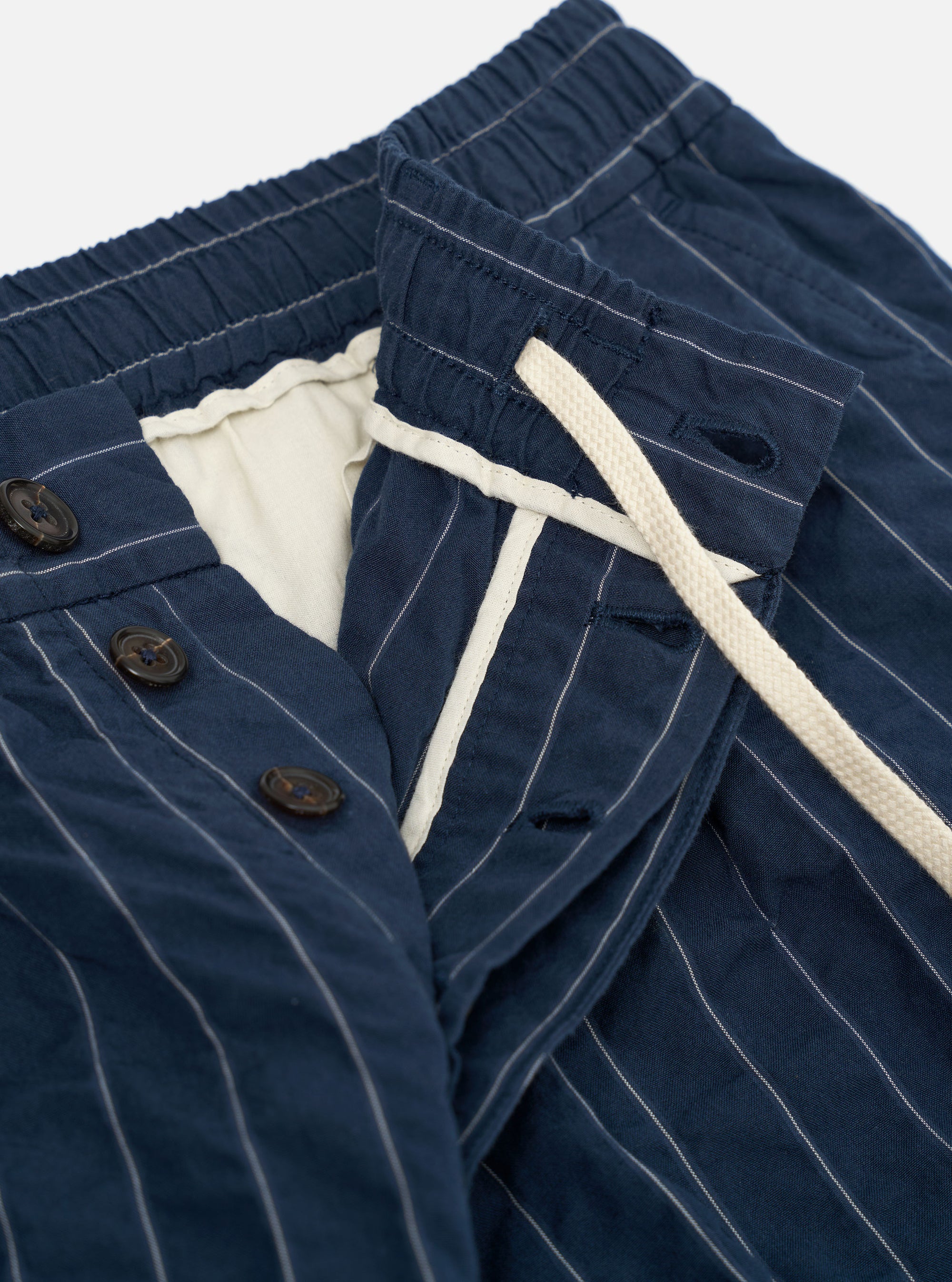 A pair of Navy Chester Stripe Oxford Pants is displayed flat against a plain white background. The trousers feature a navy blue fabric with thin vertical white stripes, a wide-leg silhouette, a pleated front, and a drawstring waistband.