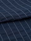 A close-up fabric swatch of the Navy Chester Stripe Oxford Pant is shown against a plain white background. The image highlights the fine vertical pinstripe pattern on the navy blue cotton fabric, showcasing the material's texture and detail.