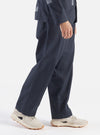 A model walks in a studio setting wearing the Navy Twill Duke Pant. The pants are navy and made of twill. The background is a bright white.