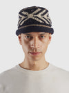 A full studio product view of the cableami® Navy Wool Jacquard Watch Cap set against a plain white background, highlighting its folded cuff, ribbed brim, and intricate jacquard-knit pattern throughout the crown.