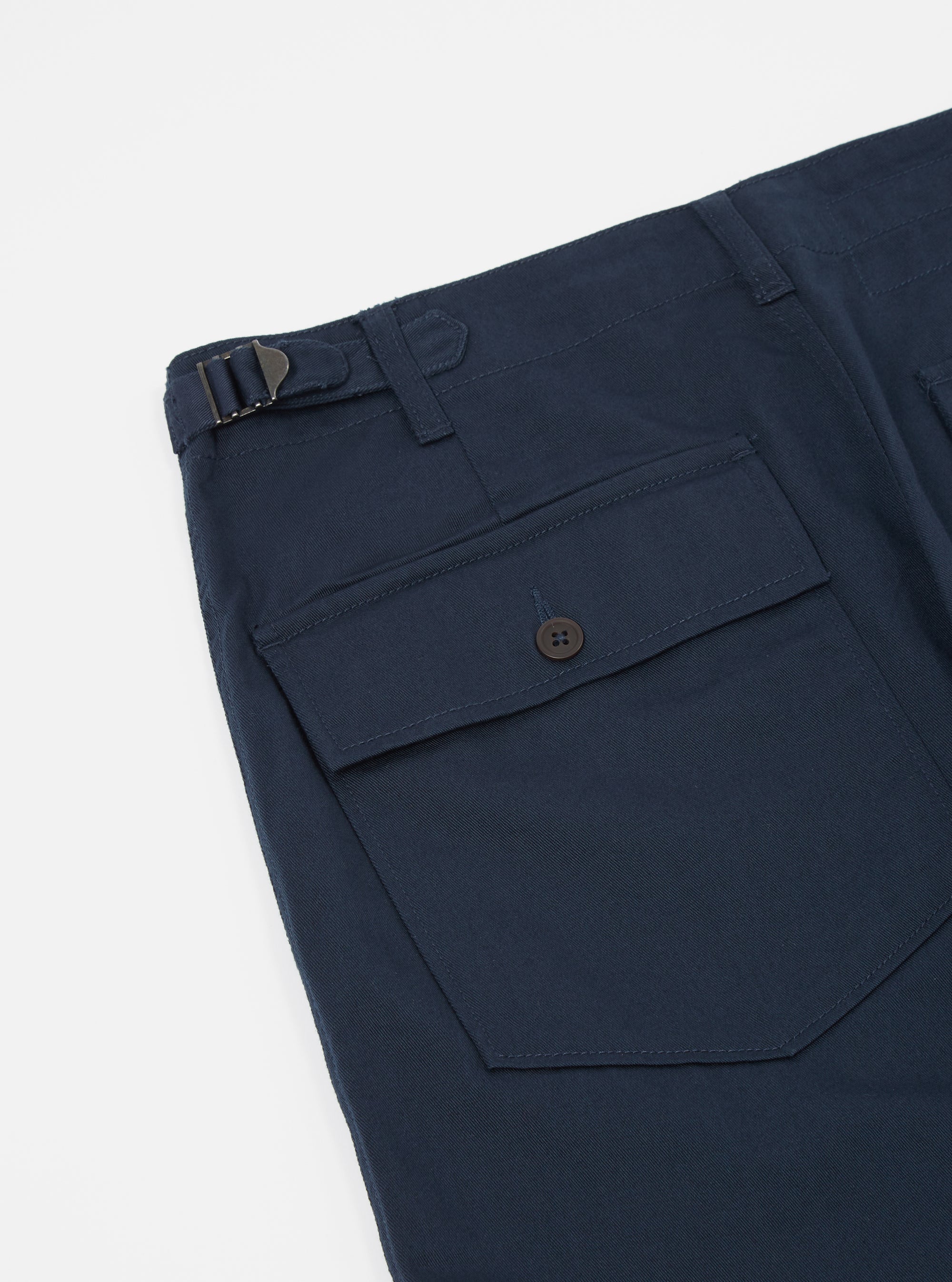 Close-up of the Navy Twill Fatigue Pant (Undarted) on a white background. Shows the twill fabric, side pocket with button, and adjustable waist buckle.