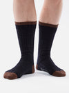 Close up of a person wearing Navy Wool Hike Sock. The socks are navy blue with brown toes and cuffs. The background is white.