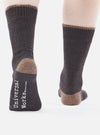 Close-up of a person wearing Charcoal Alpaca Wool Sock. The socks are charcoal with a brown toe and cuff. The background is white.