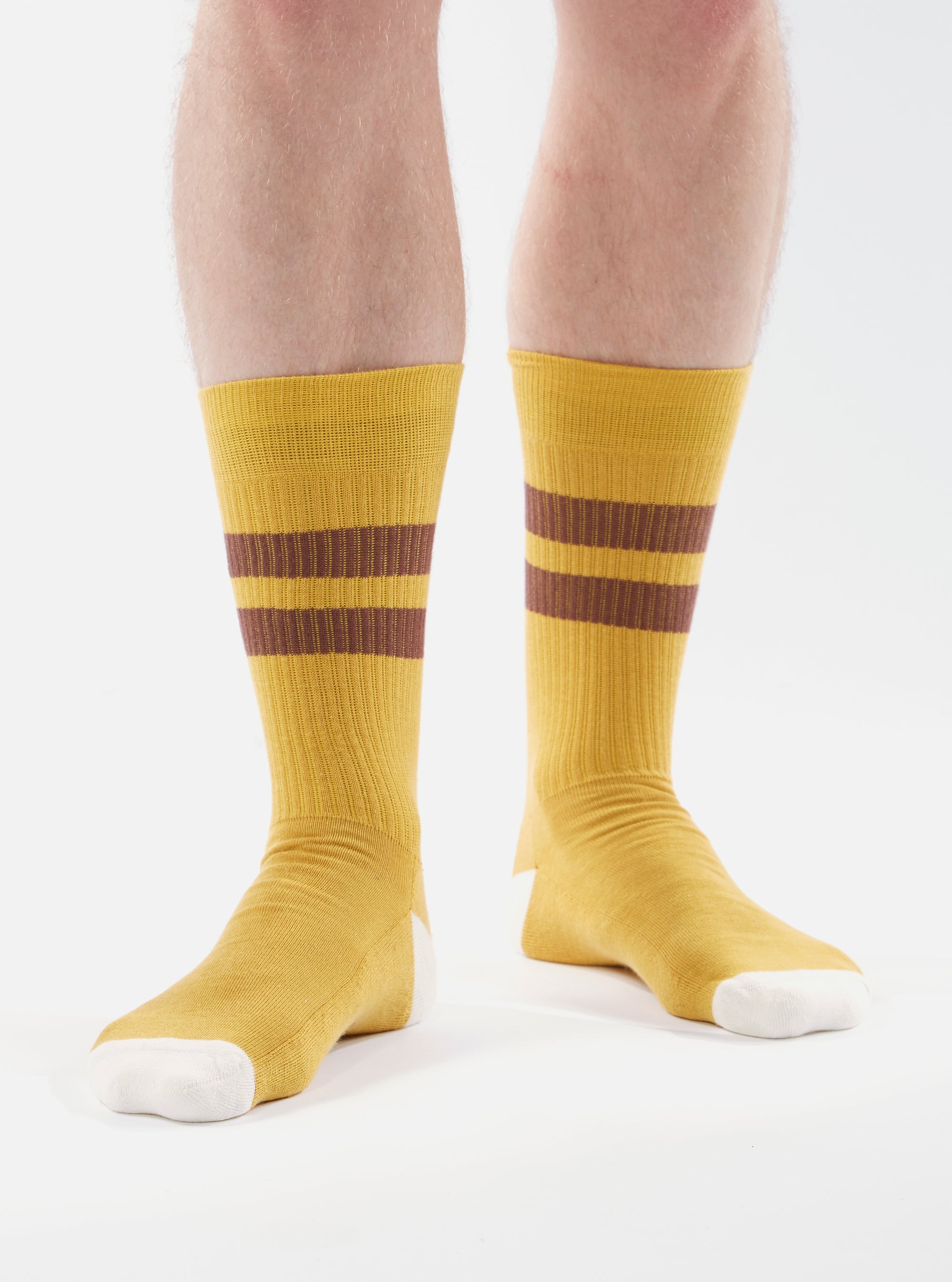 A model wears Yellow/Raisin Cotton Rib Sport Sock, featuring yellow ribbed cotton with raisin stripes and white toes. Shot on a white background.