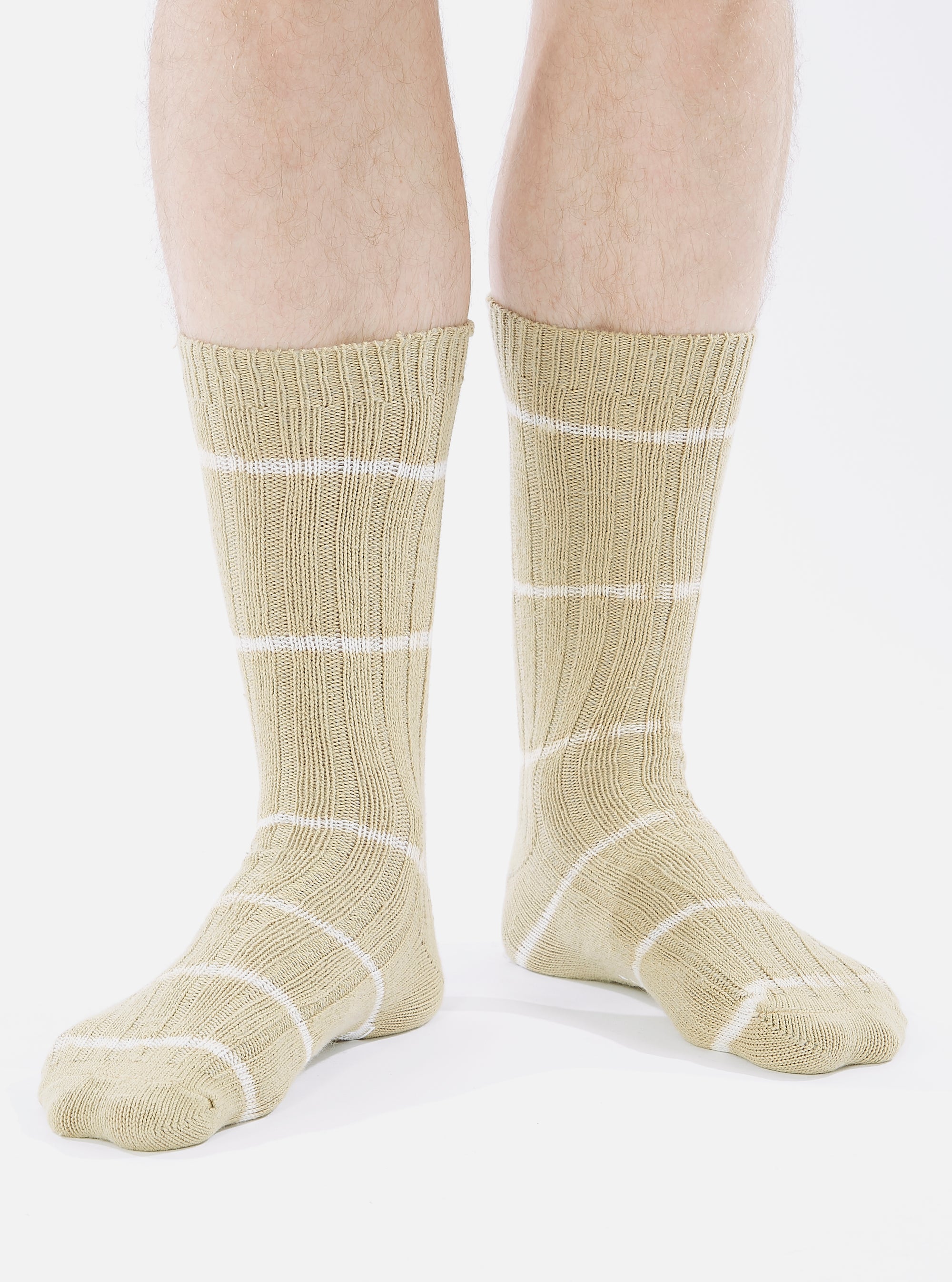 A person wearing Dark Sand Tie Dye Knit Slub Sock. The socks are tan with white stripes, knit material, on a white background.